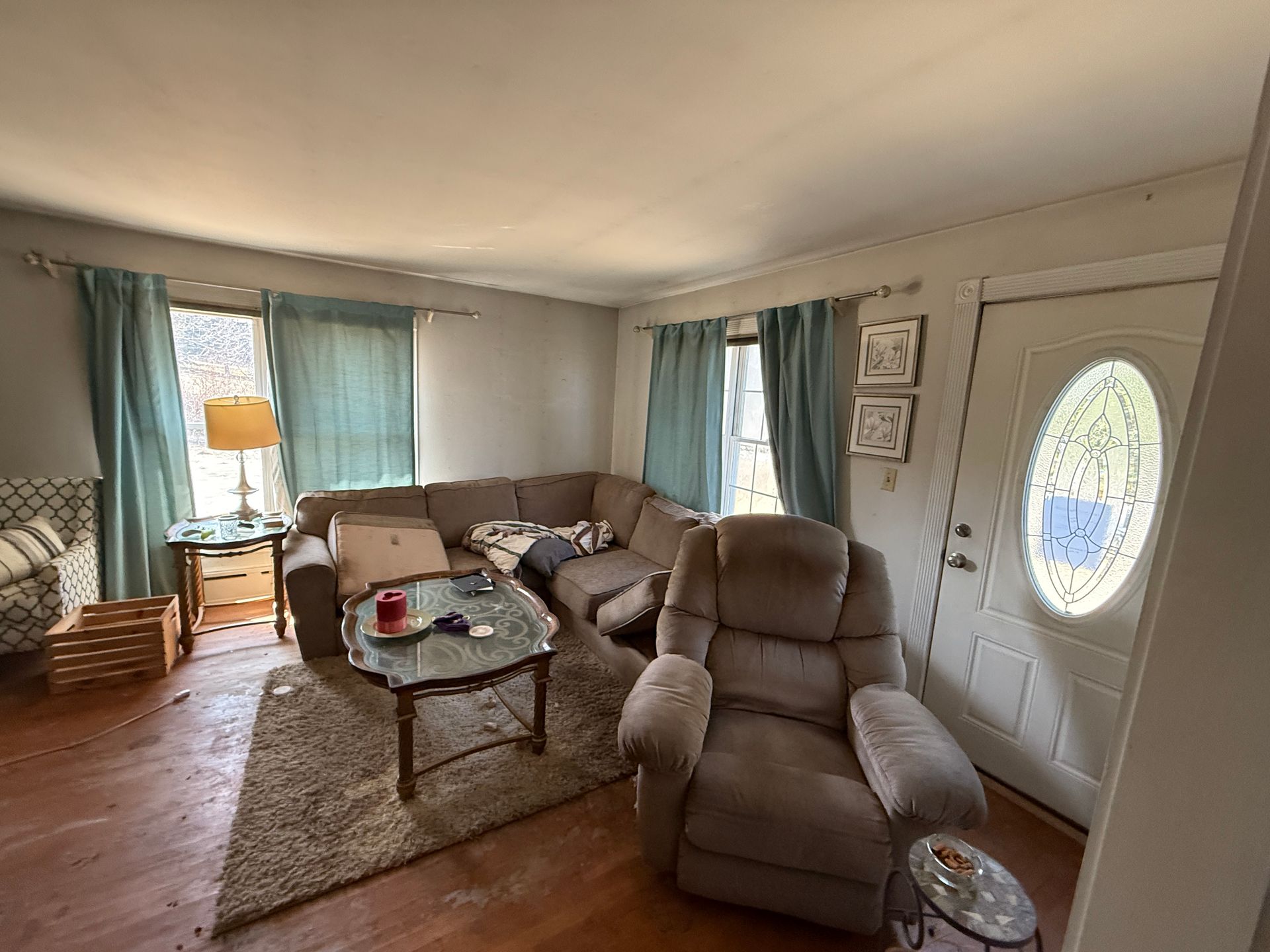 Living room with a sectional sofa, recliner, glass coffee table, and blue curtains.