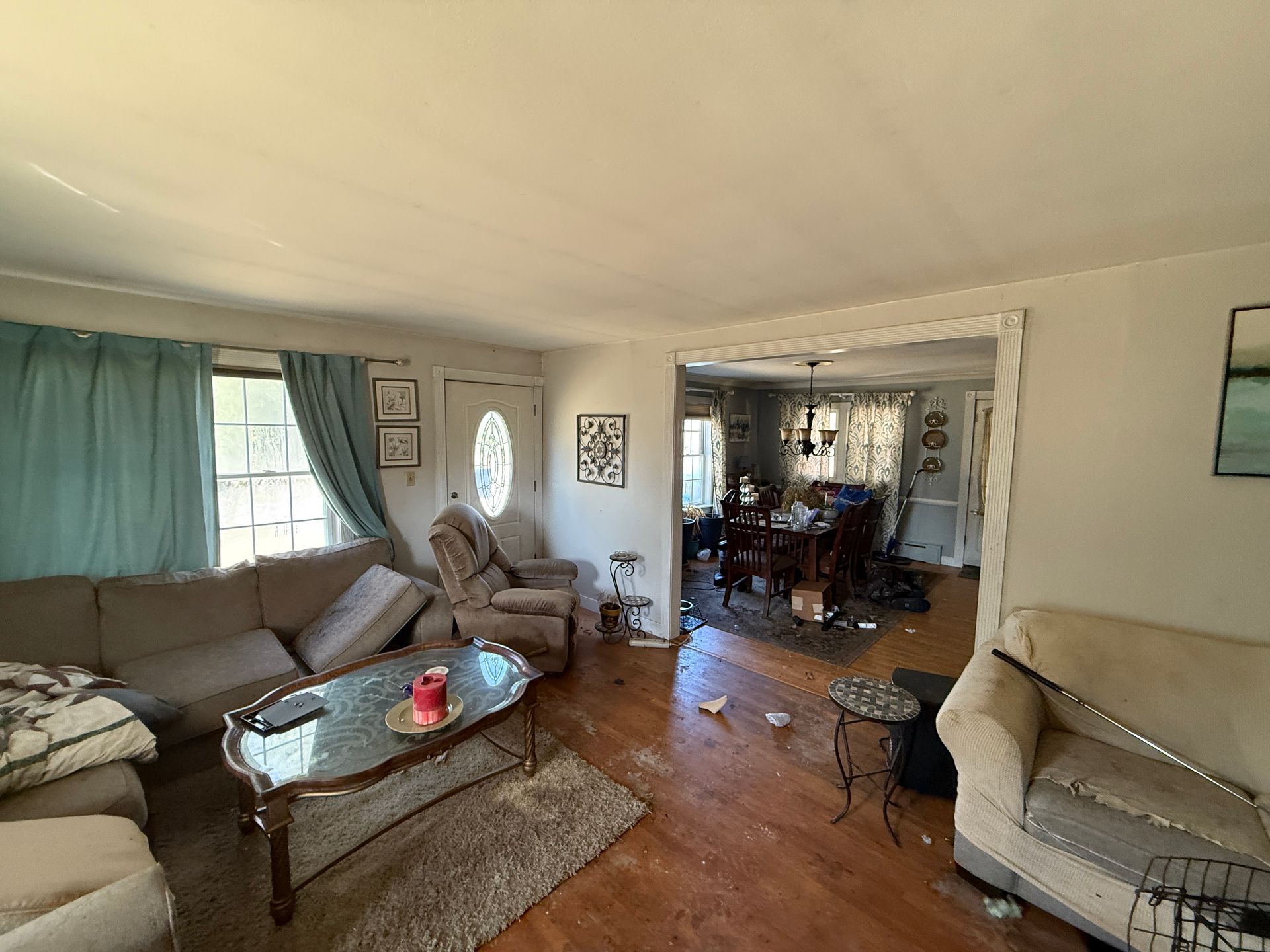 Living room with sofa, chair, and coffee table. A dining area visible in the background.