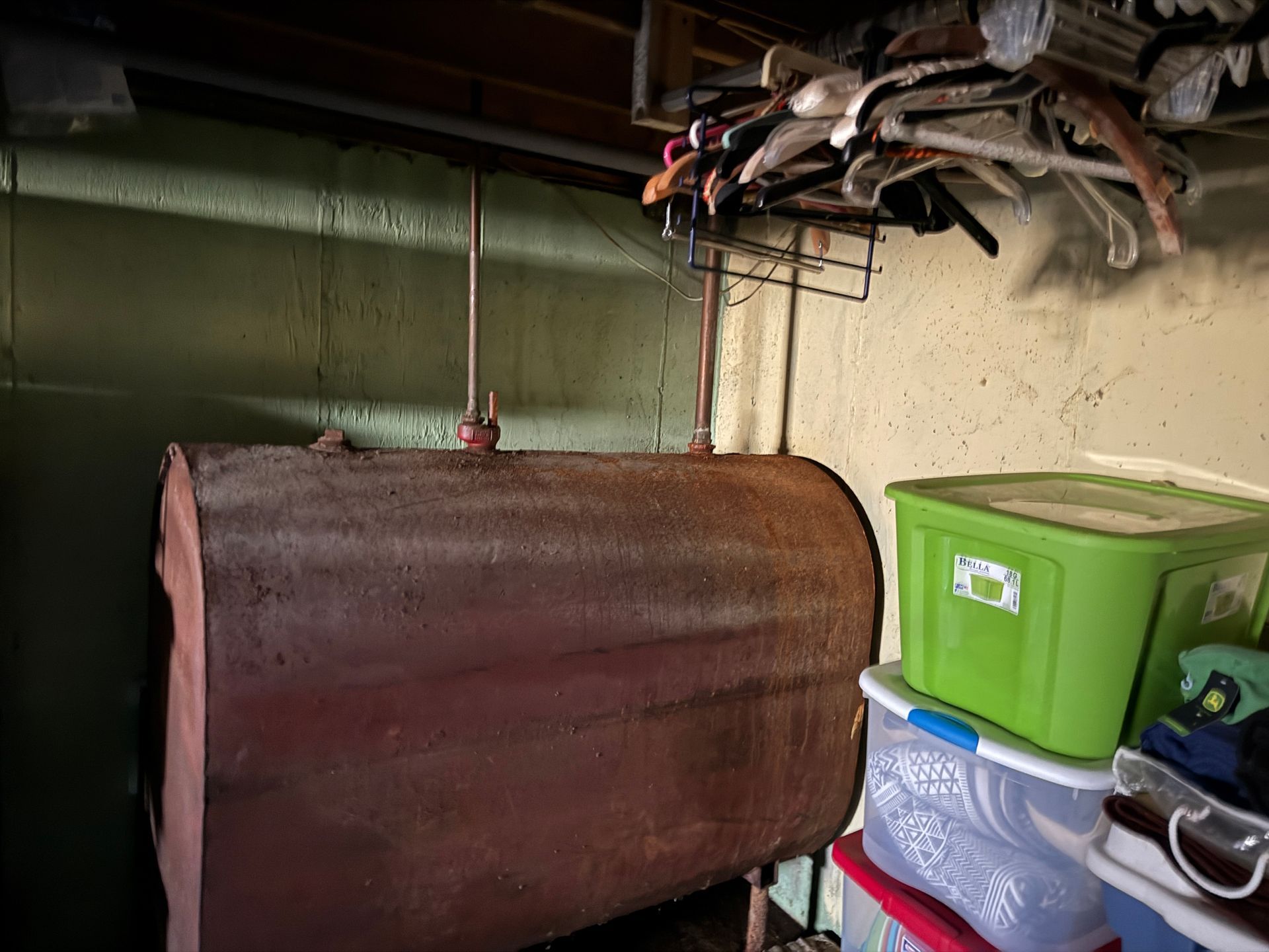 Horizontal oil tank in a basement storage area, with storage bins and miscellaneous items.