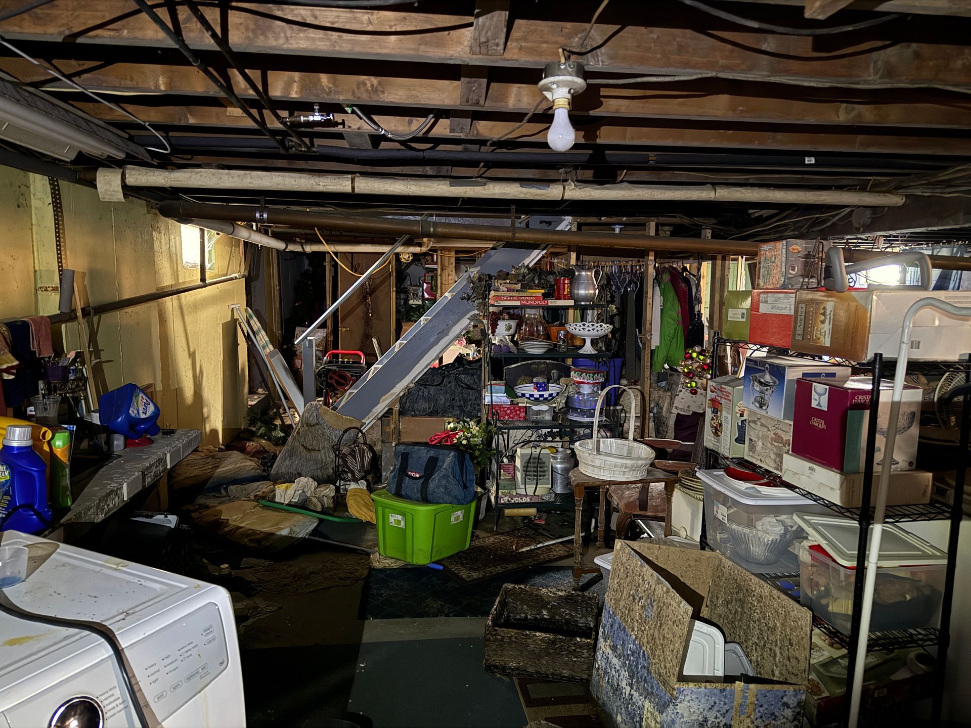 Basement with exposed beams, storage boxes, and a washing machine.