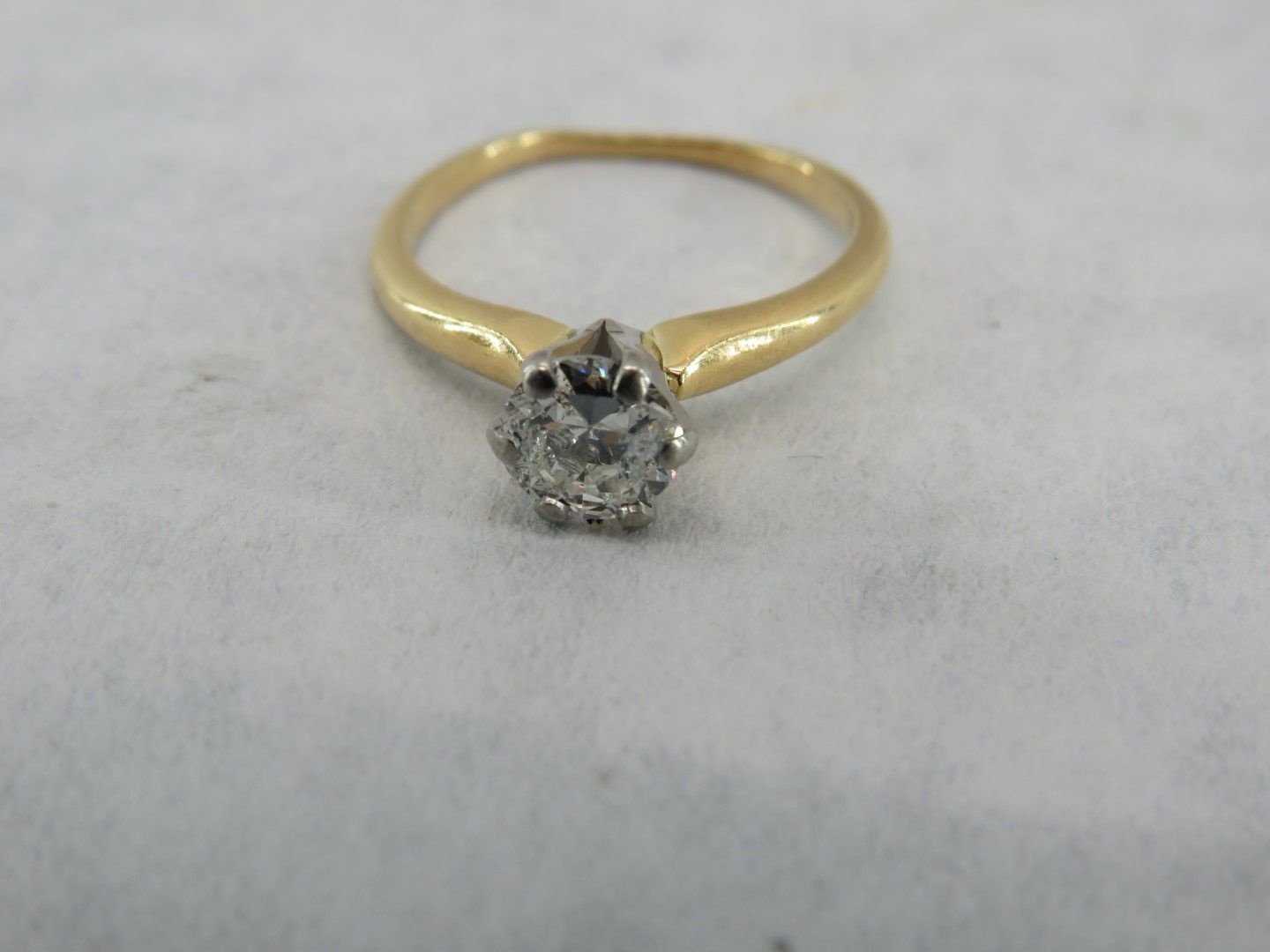Gold ring with a white diamond center stone.