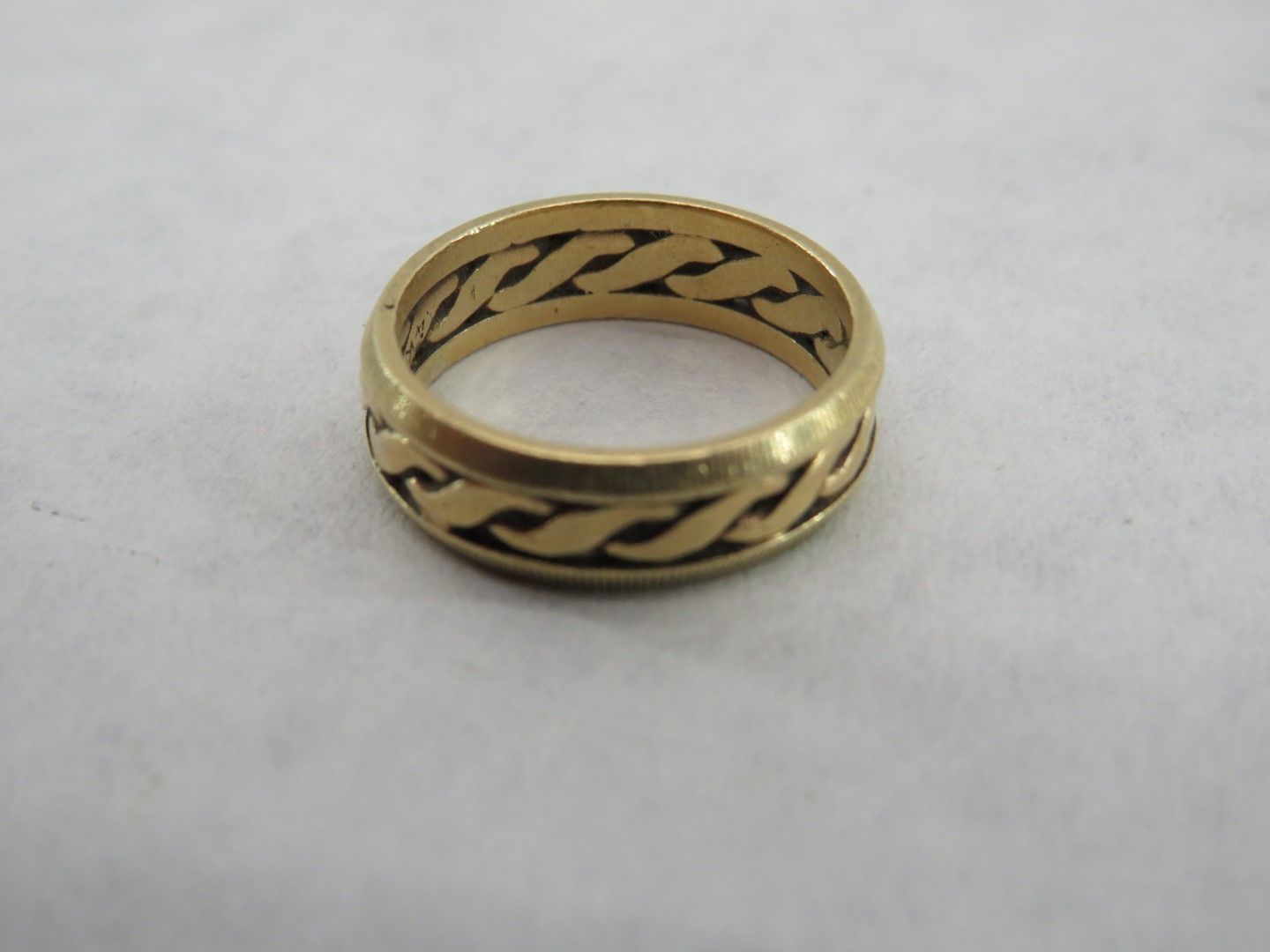 Gold ring with braided design around the band.