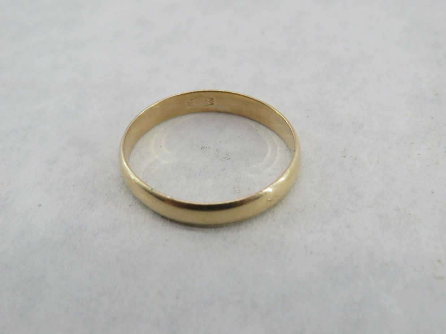 Gold ring on a white surface.