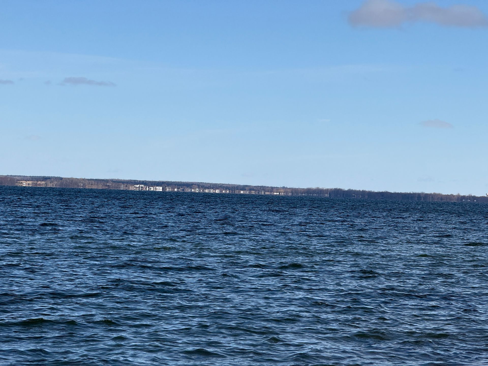Dark blue water with a distant shoreline under a clear, blue sky.