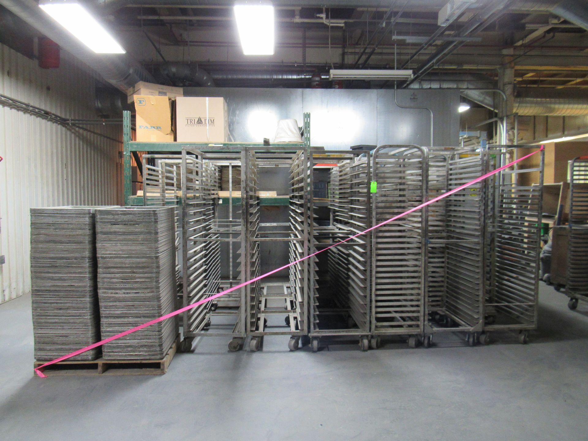 Stacks of metal trays and racks inside a warehouse.