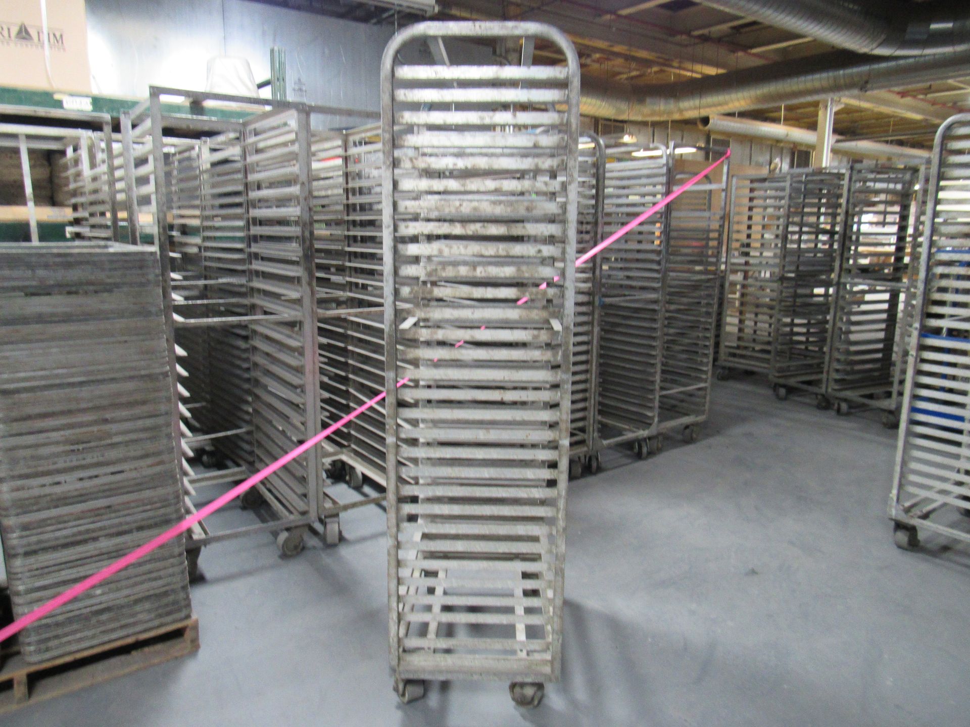 Metal racks on wheels in a factory setting, possibly for baking or food storage.