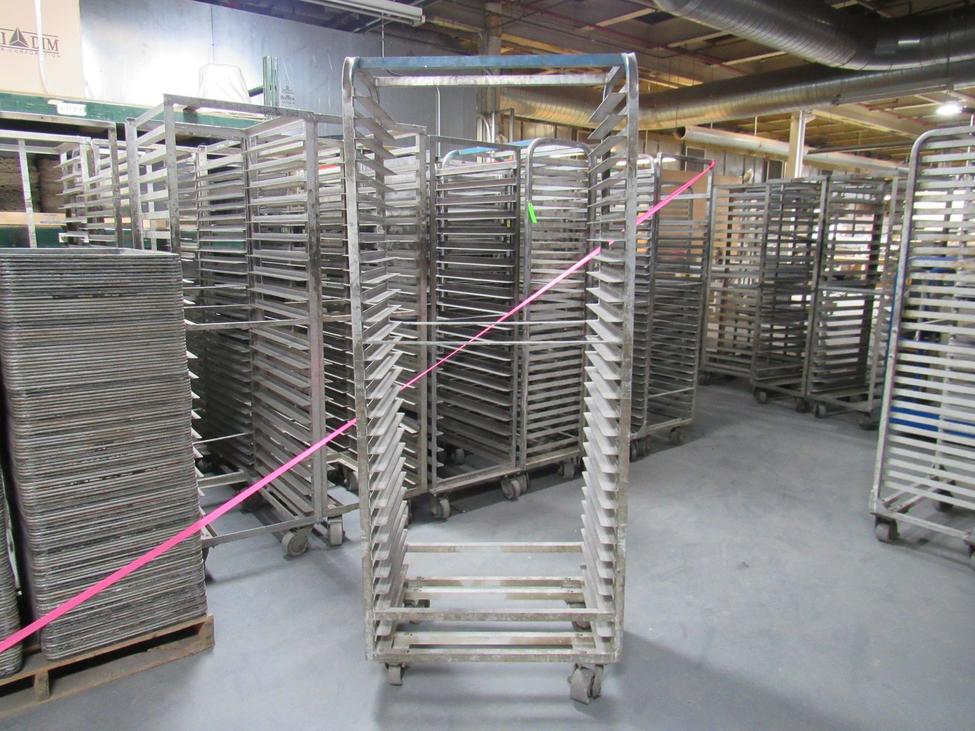 Metal racks on wheels, stacked with trays, inside an industrial setting.