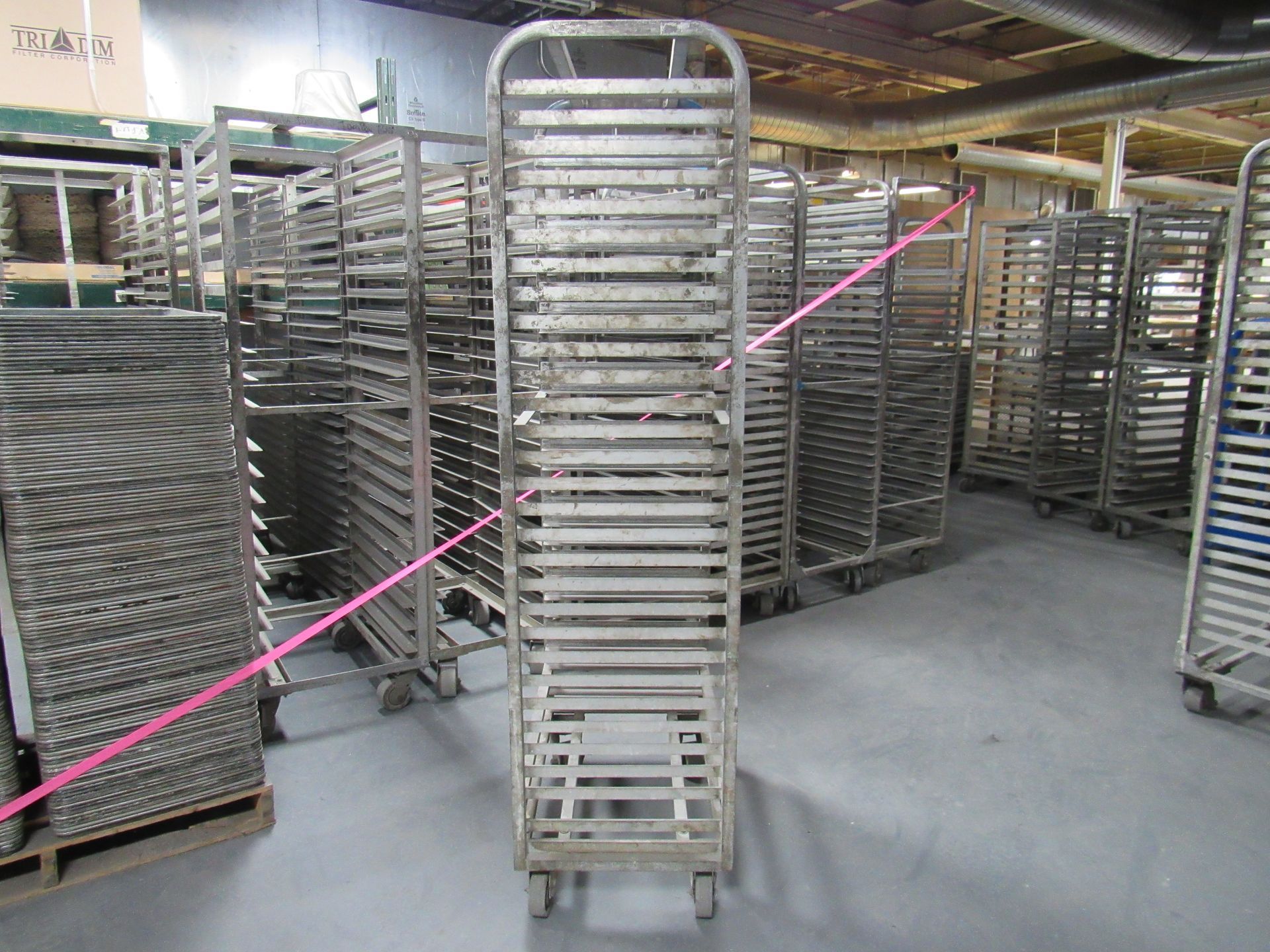 Rows of metal tray racks on wheels inside a warehouse.