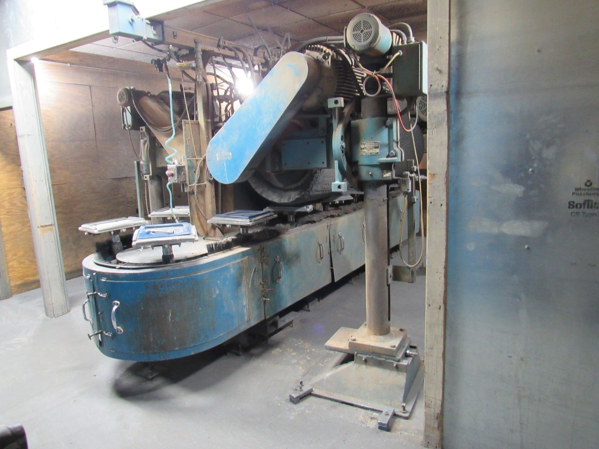 Blue industrial machine in a workshop, likely for cutting or shaping materials.