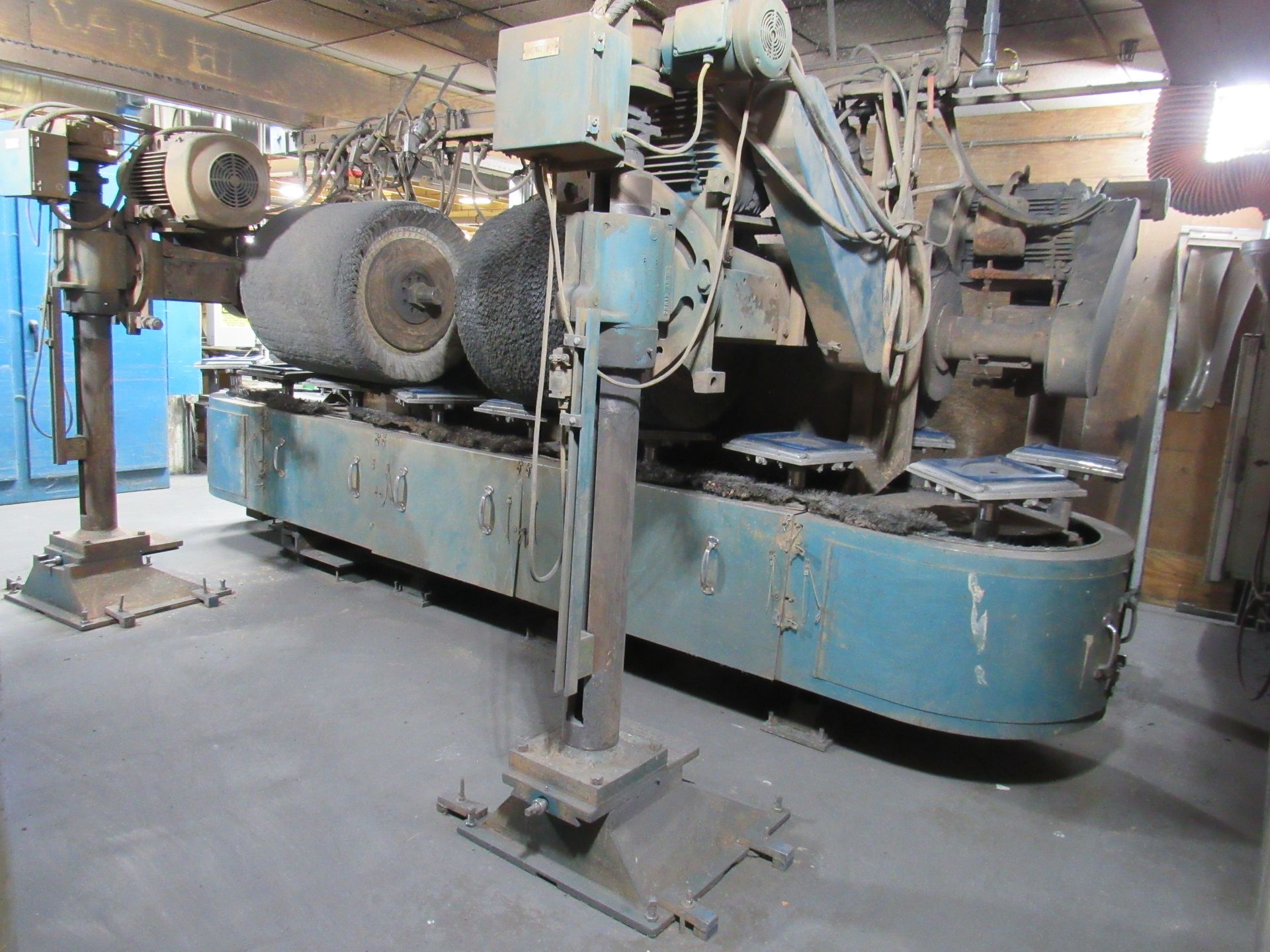 Blue and grey industrial polishing machine in a factory setting.