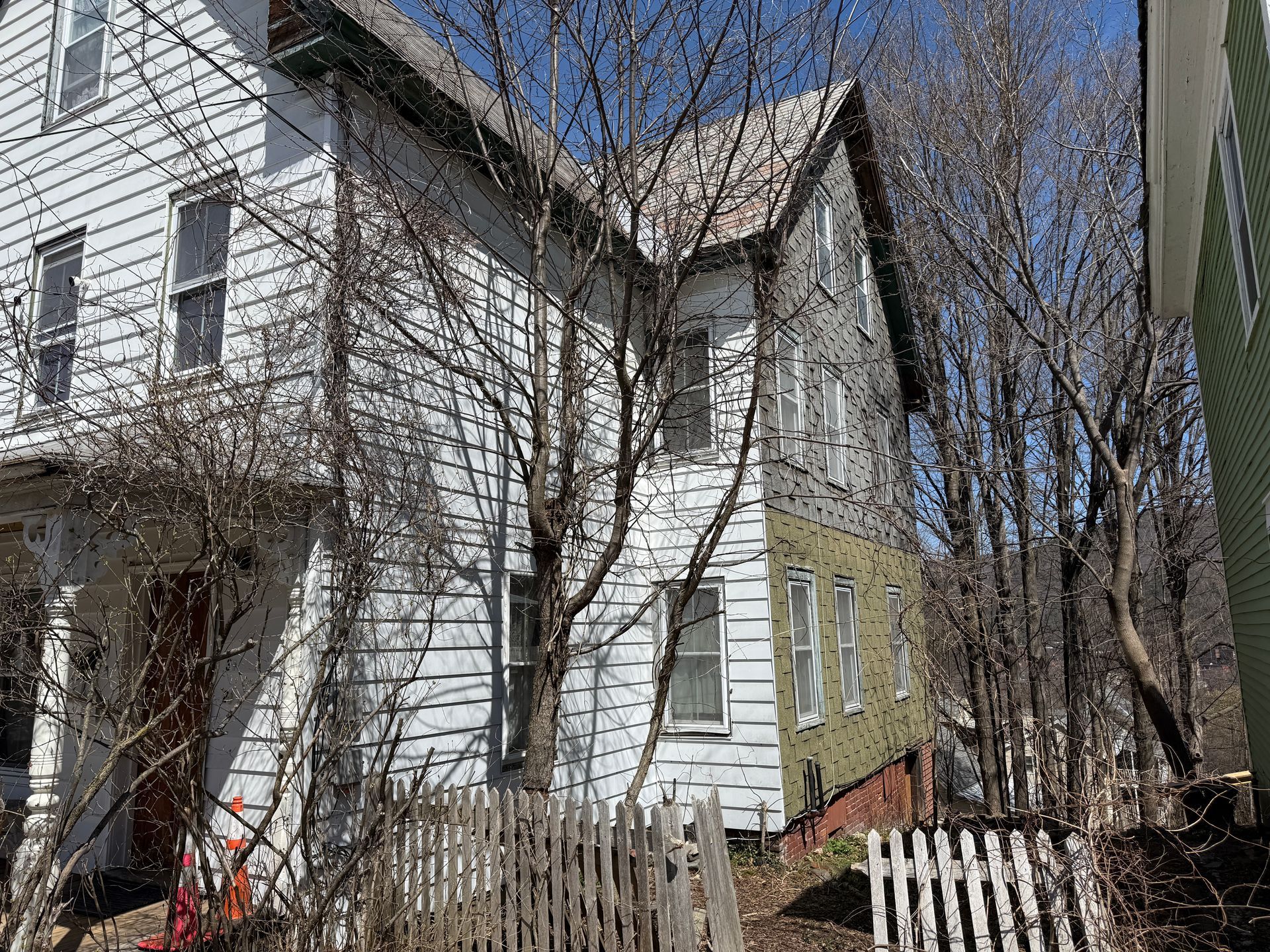 White house with white siding, bare trees, and a wooden fence.