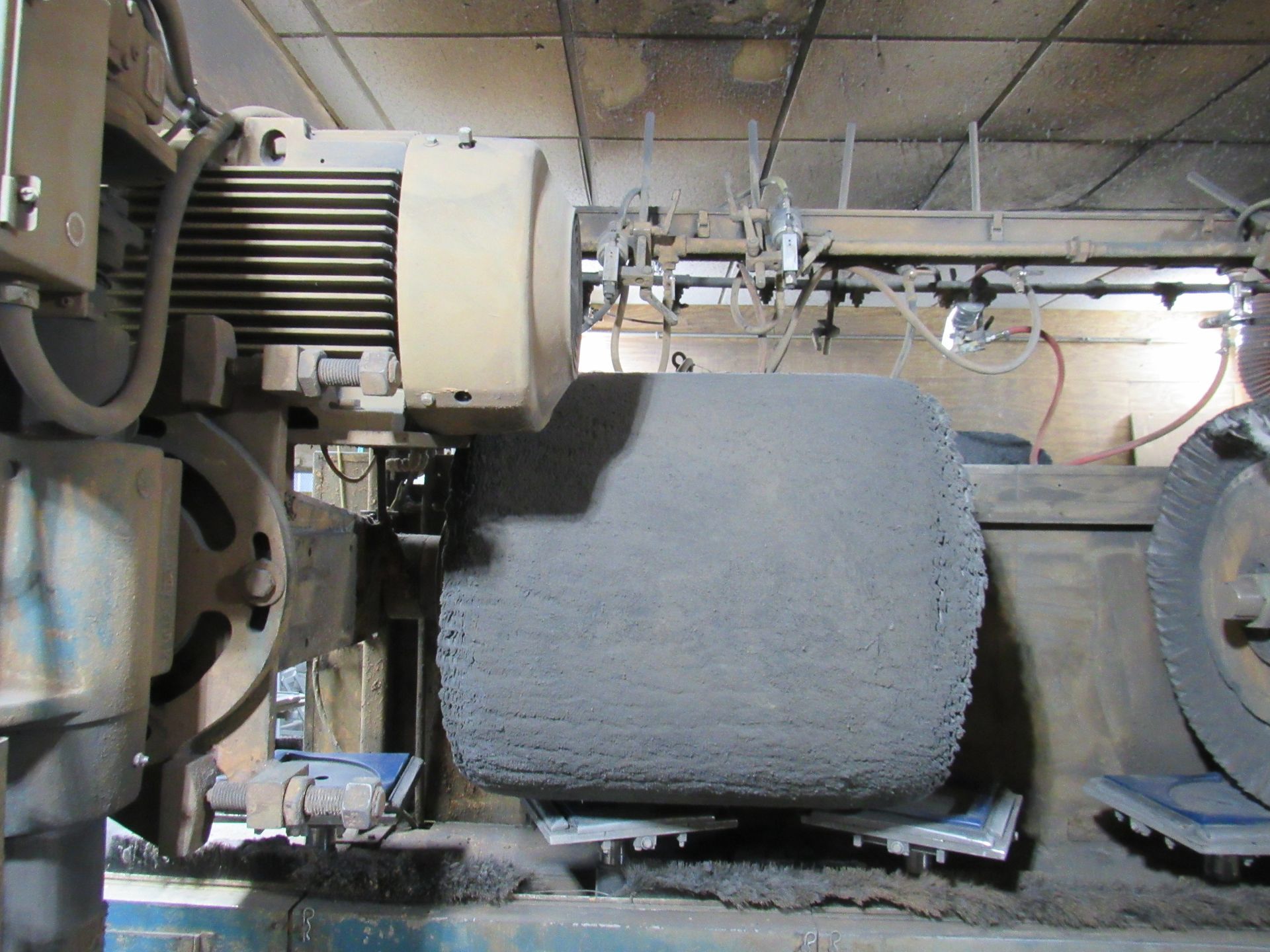 Large industrial machine with cylindrical polishing wheel.