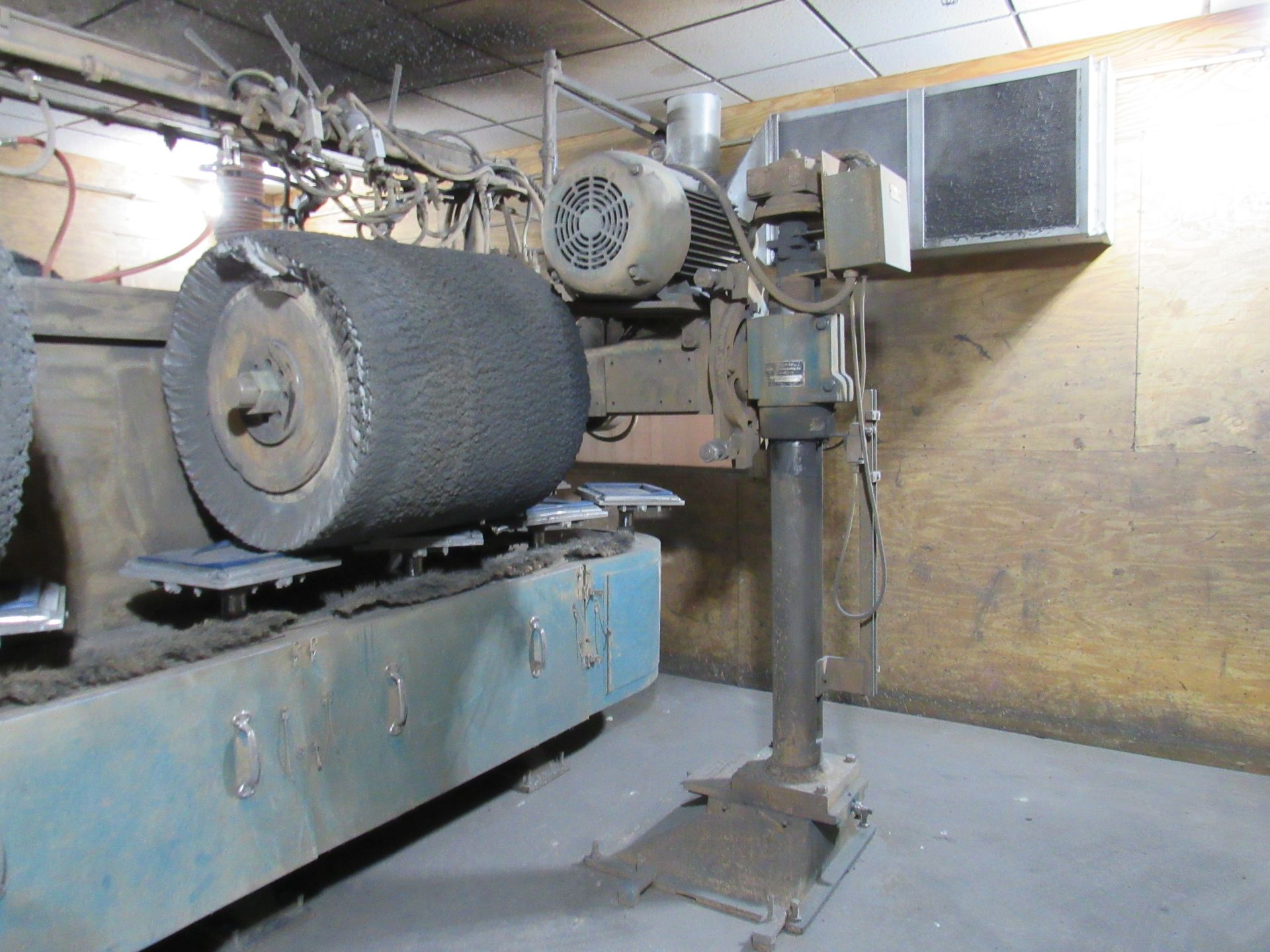 A large, industrial buffing machine with a rotating brush, foot pedal, and electric motor.