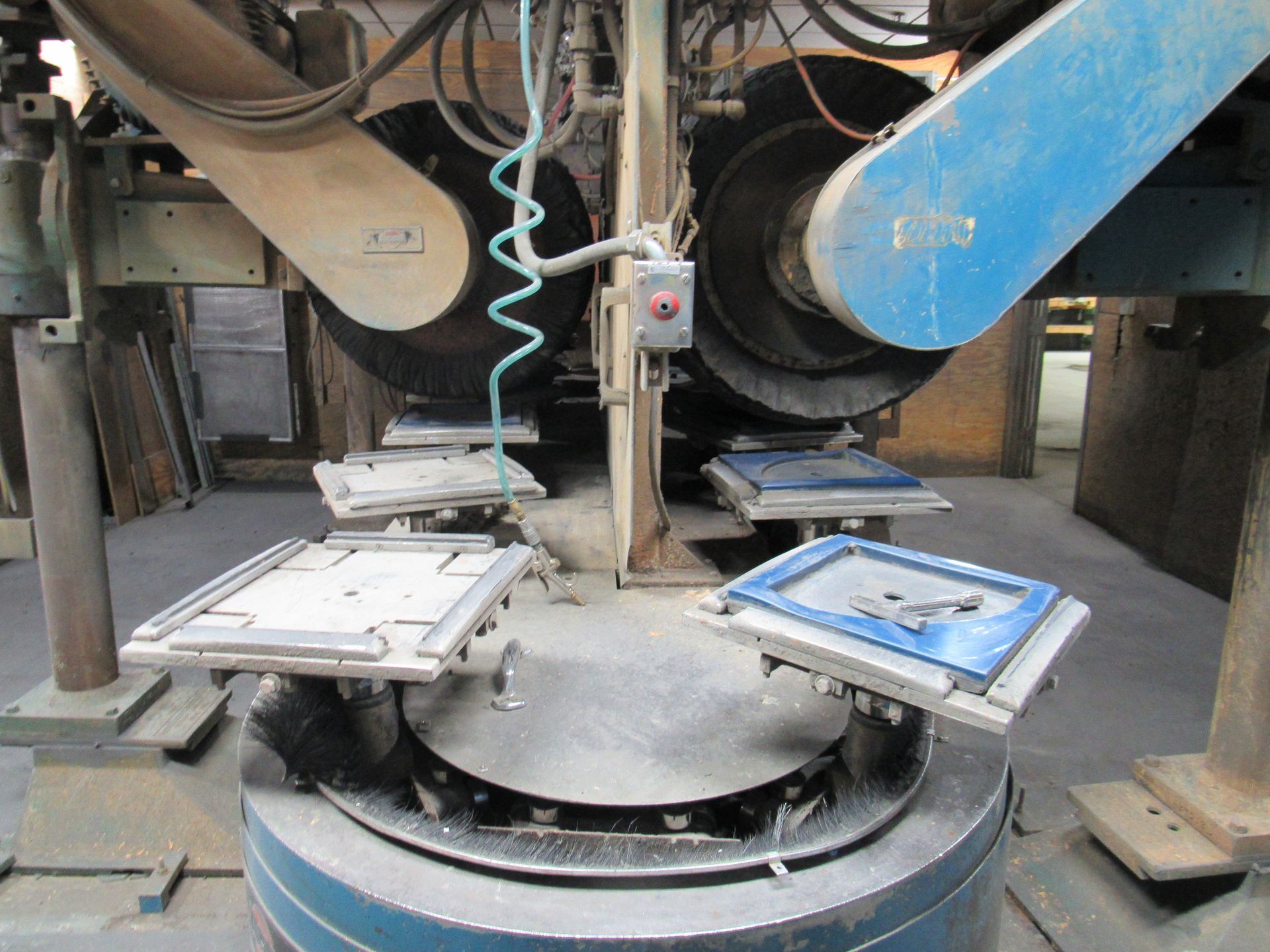 Industrial machine with rotating platforms grinding frames.