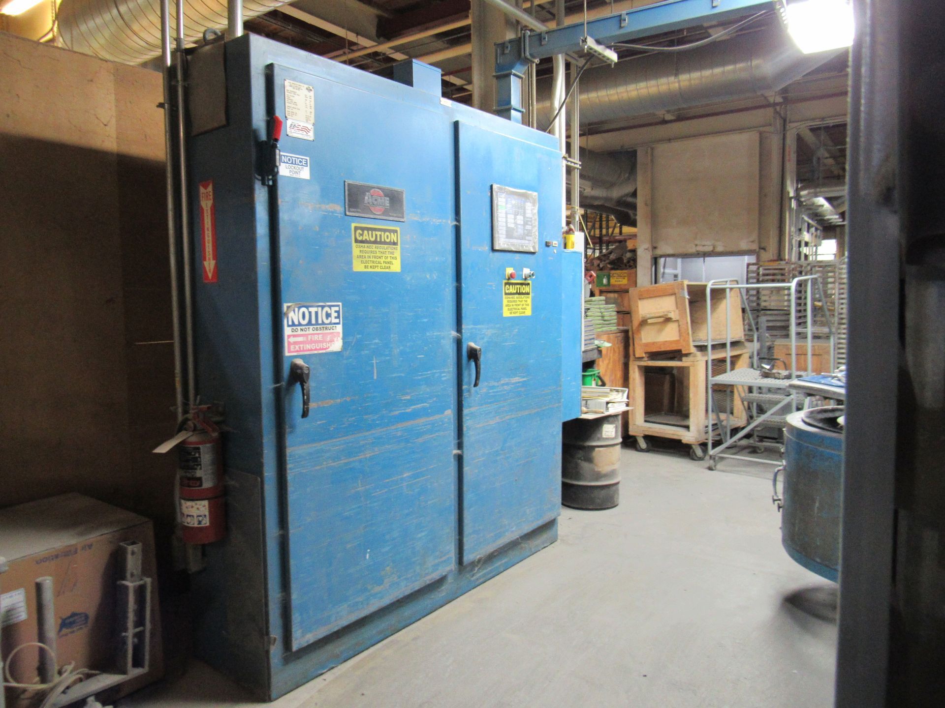 Blue industrial cabinet with safety signs in a factory setting.