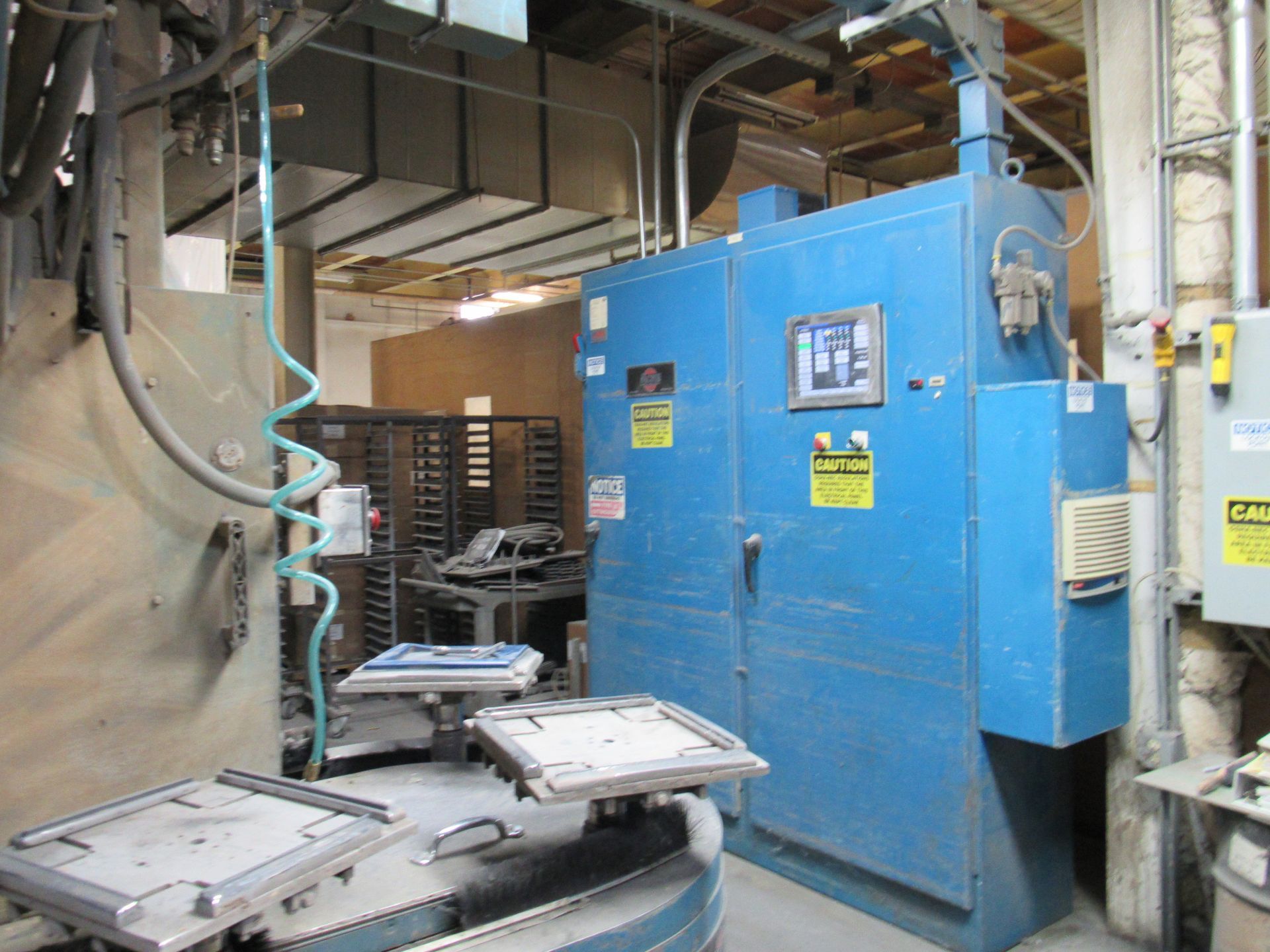 Blue industrial oven in a factory setting with loading trays.