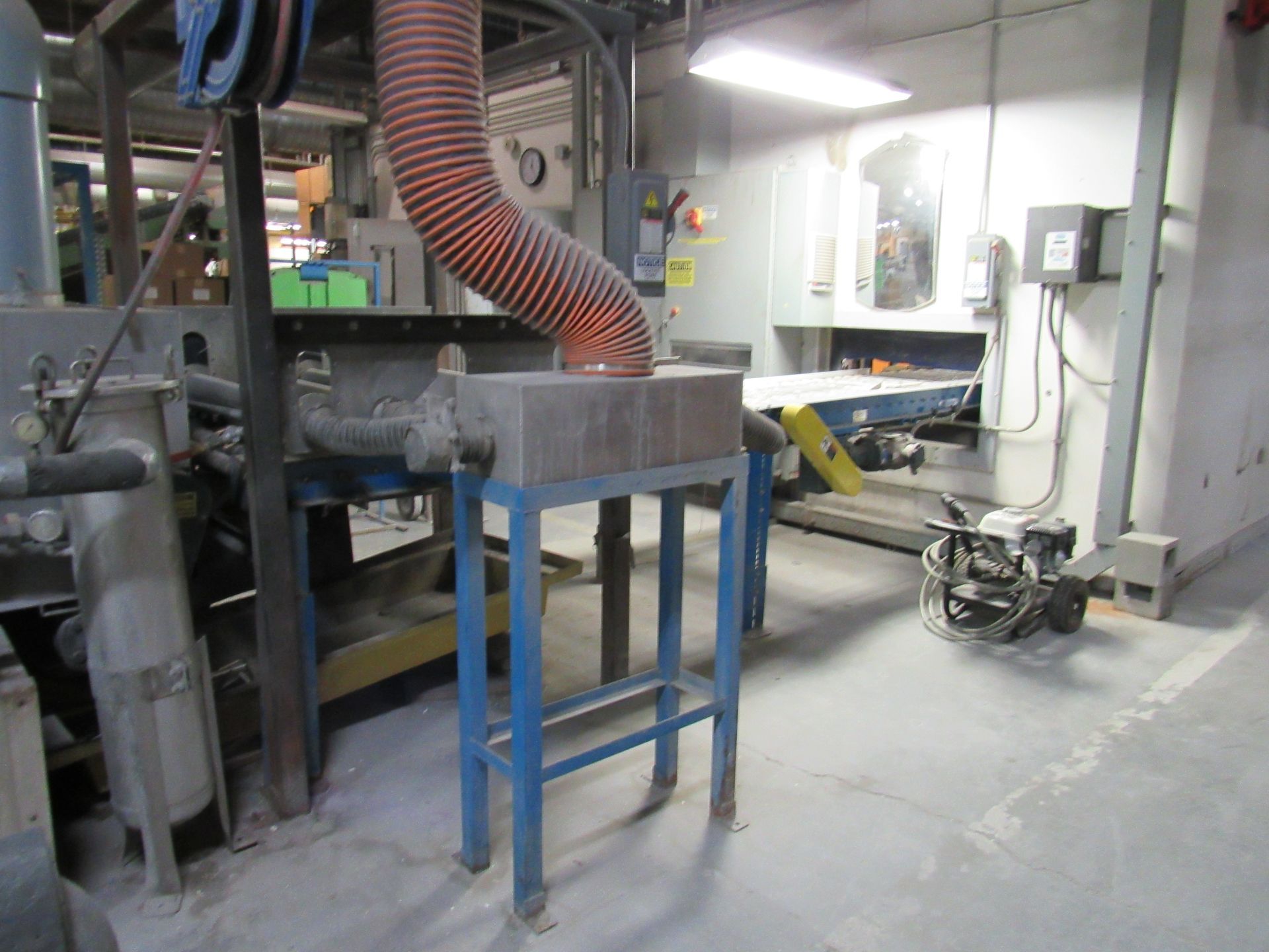 Industrial setup with a red-hot object, orange hose, and blue metal stand.