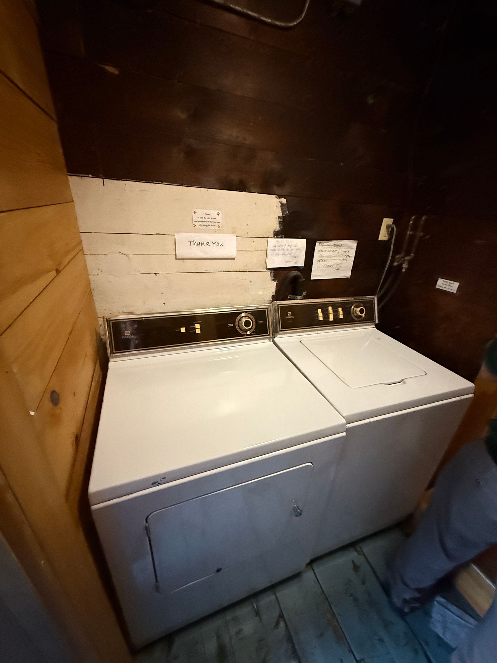 Washer and dryer in a laundry area with signs on the wall.