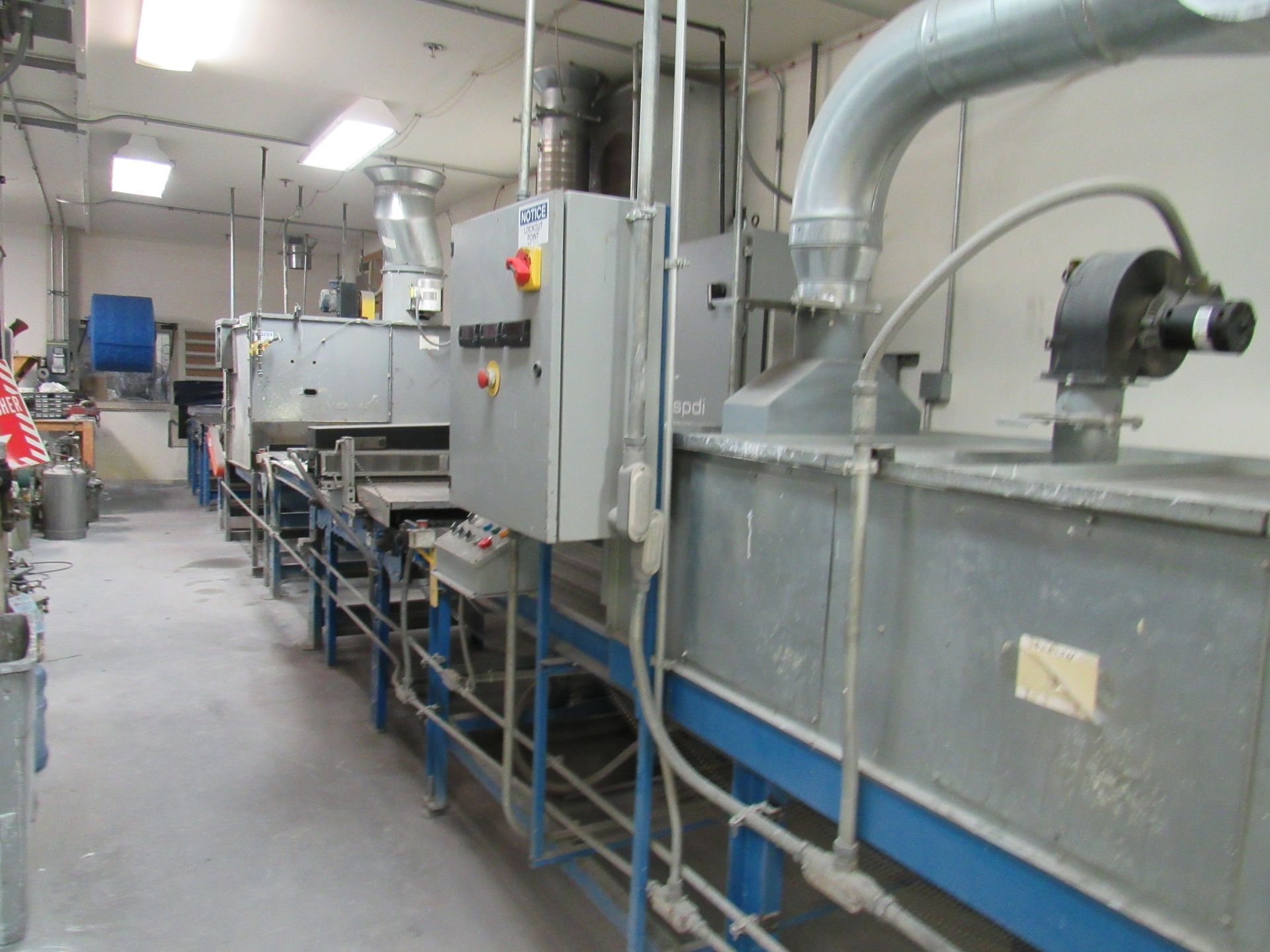 Industrial equipment in a workshop, with metal machinery, control panels, and ductwork.