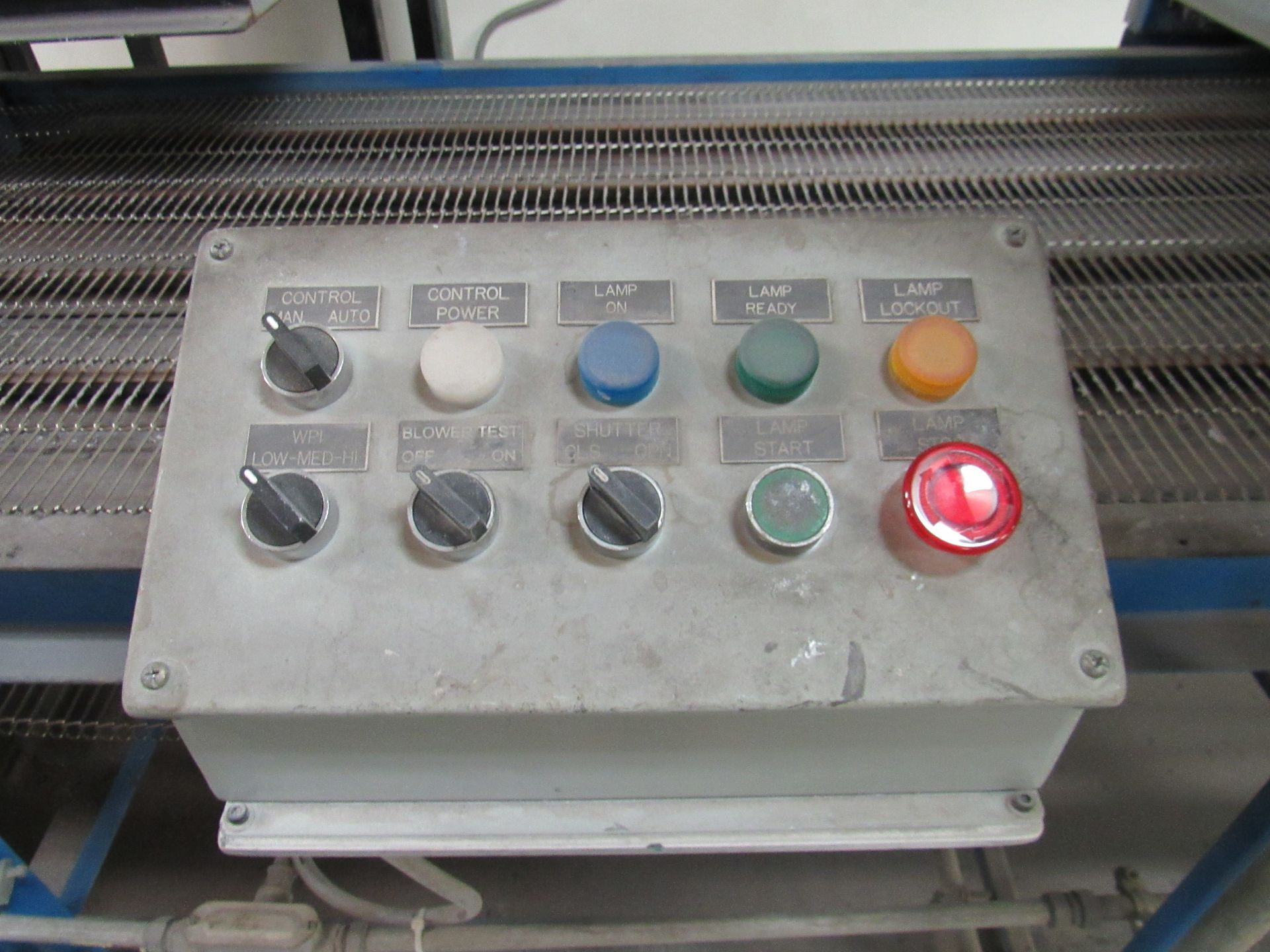 Control panel with knobs and buttons of various colors; the red button is lit.