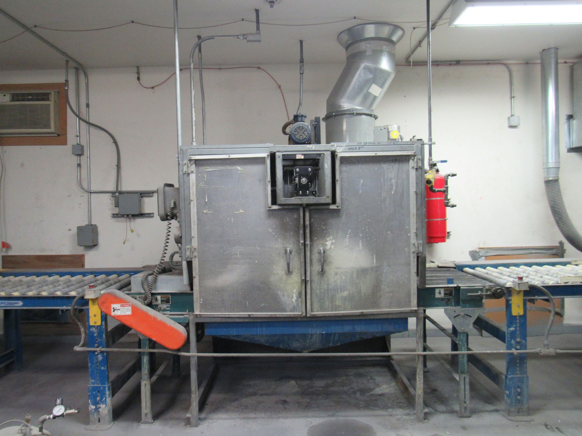 Industrial washing machine with conveyor belts, ductwork, and fire extinguisher.