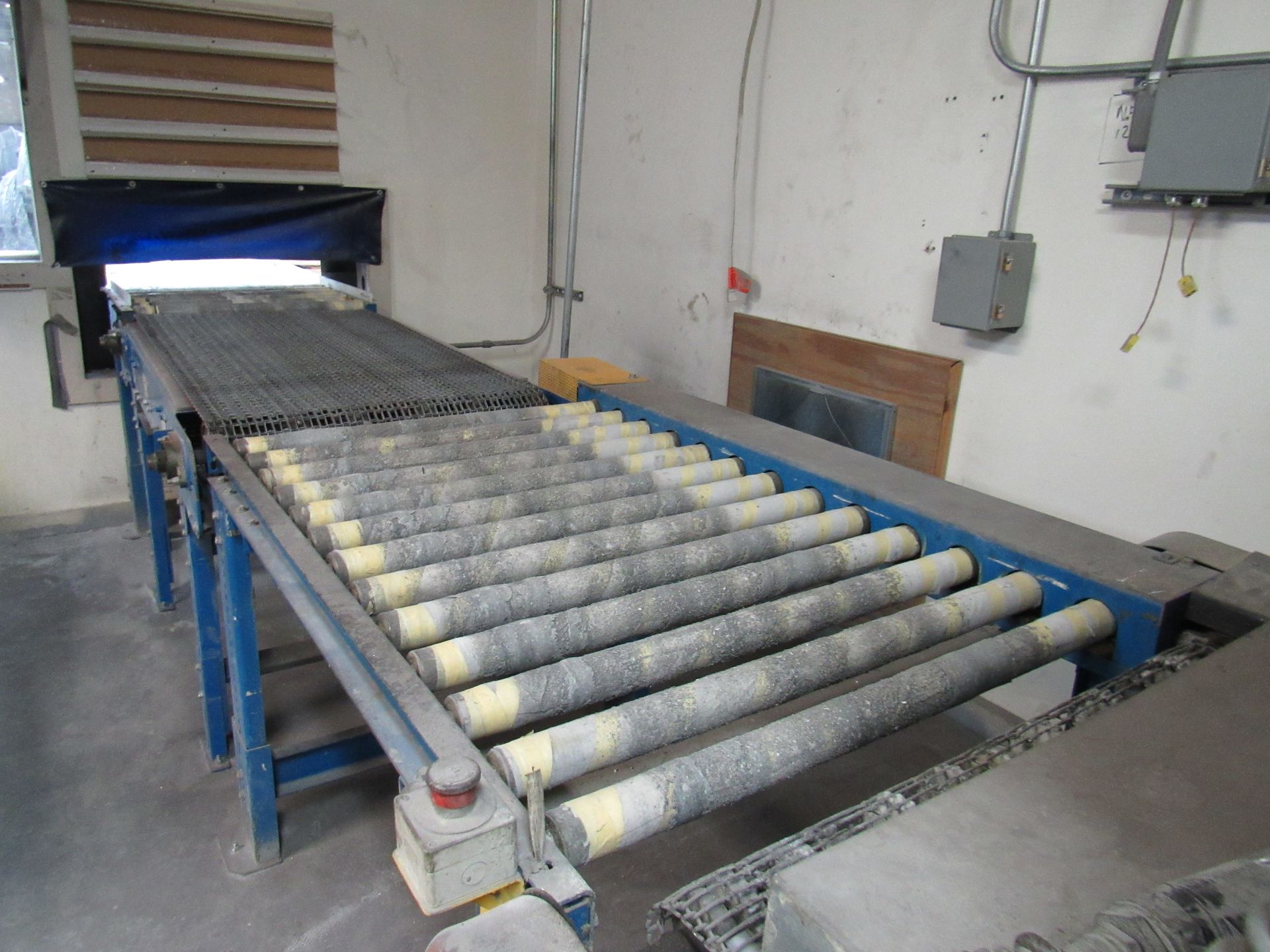 Conveyor belt in a workshop, with rollers. A light is above the belt, and controls are nearby.