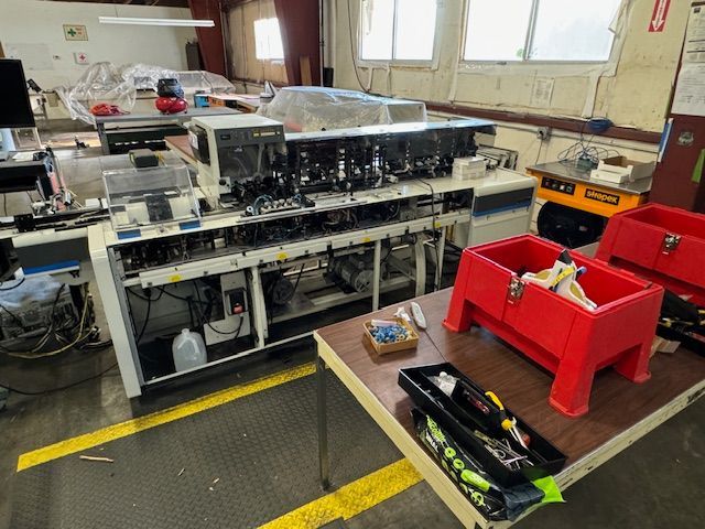 Industrial equipment in a workshop setting, with tools on a table and containers.