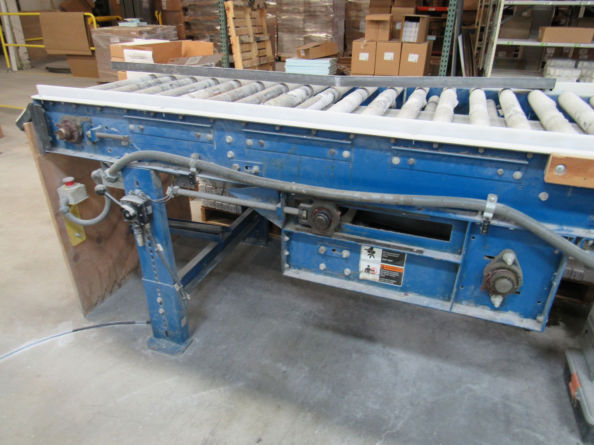 Blue industrial roller conveyor belt in a warehouse setting.