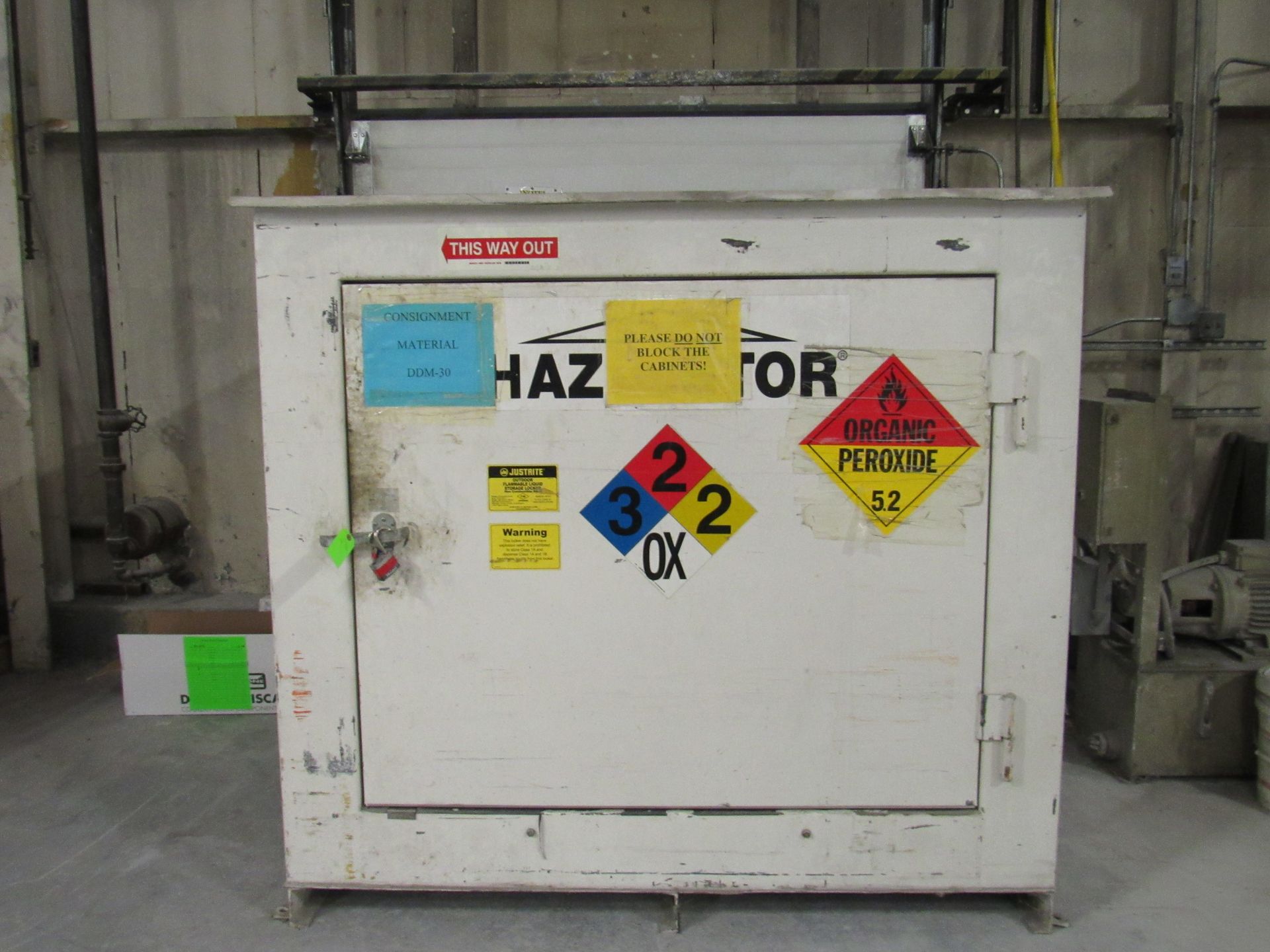White HAZMAT storage cabinet with hazard labels: flammable, corrosive, and oxidizer, indoors.