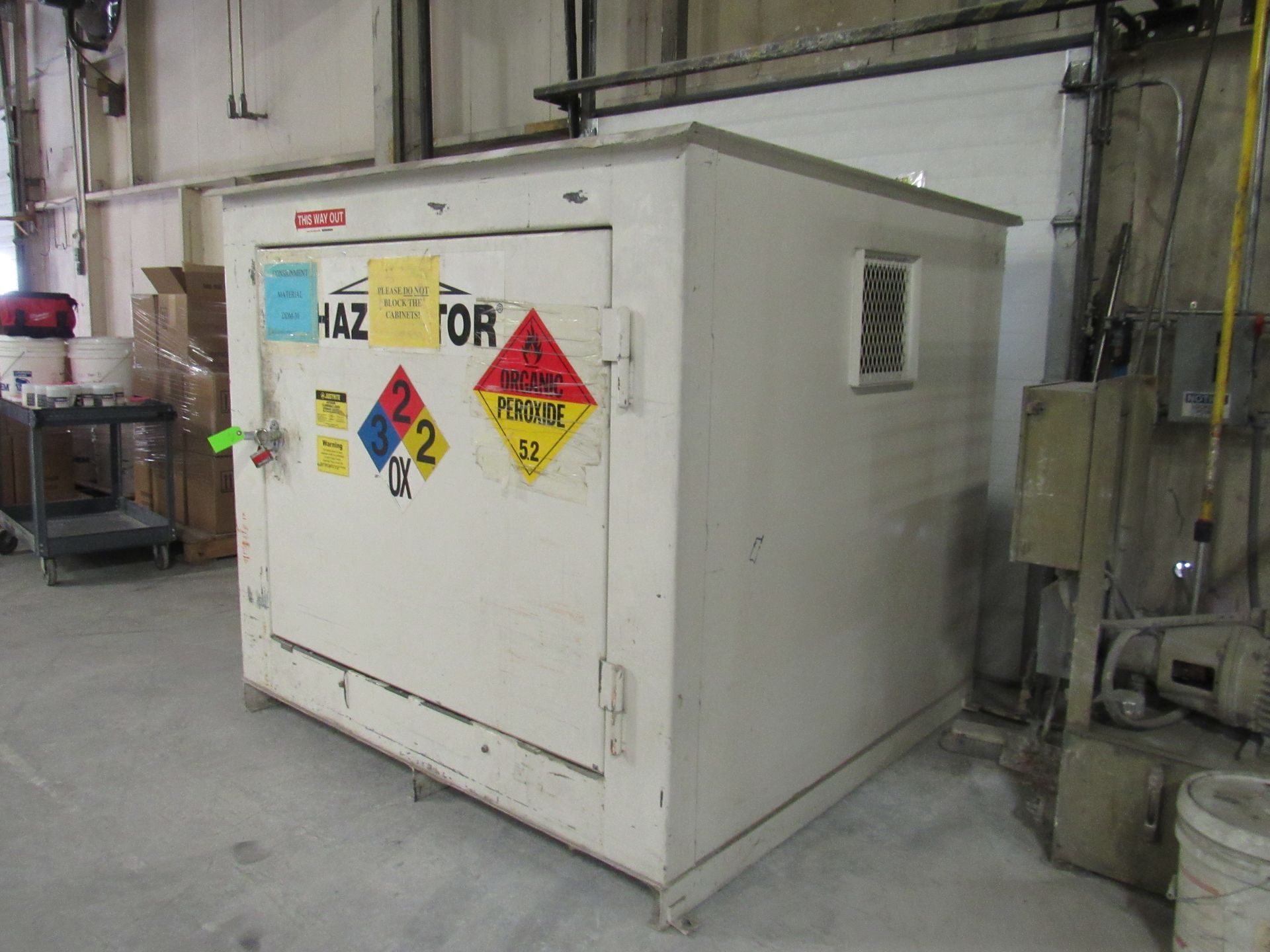 White hazmat storage cabinet with warning labels in a warehouse.