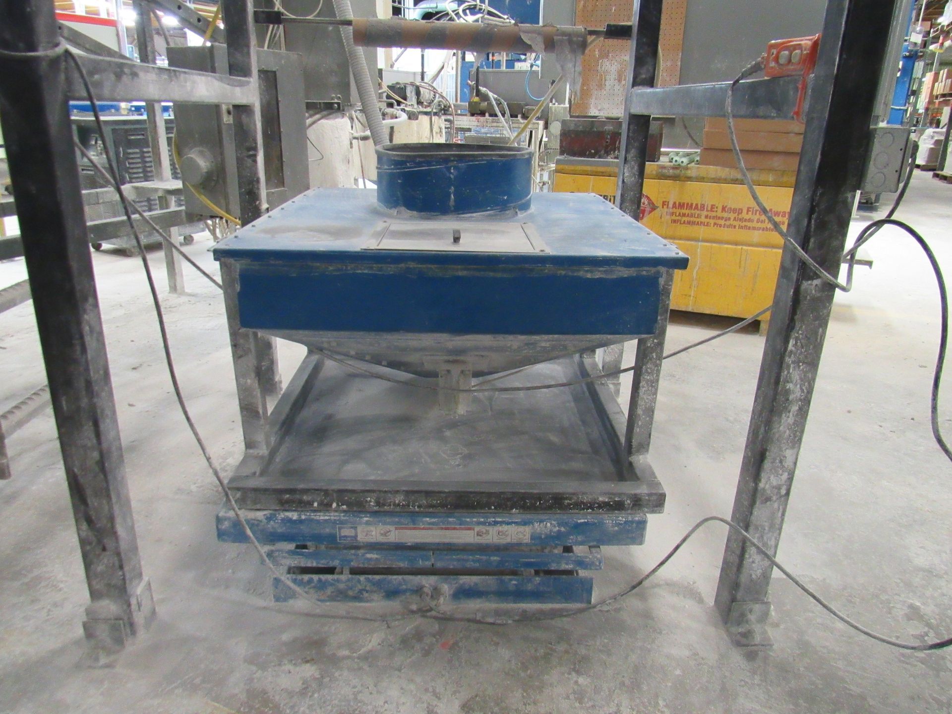 A blue and gray industrial machine with a central cone, likely for material testing in a factory.