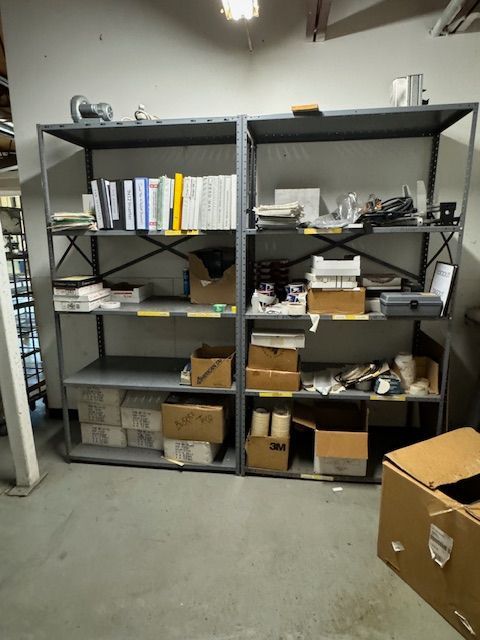 Metal shelving unit filled with boxes, binders, and supplies in a storage room.