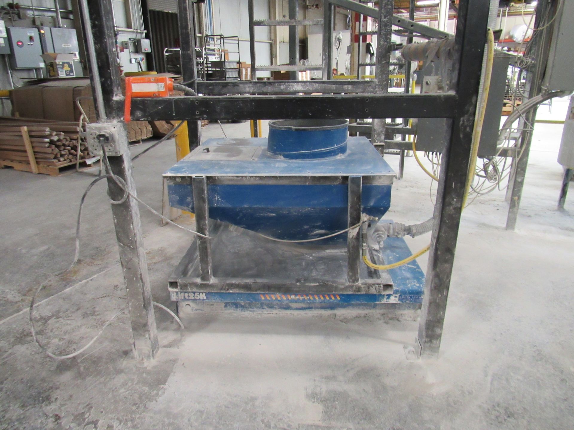Blue industrial machine on a concrete floor,  within a metal frame.