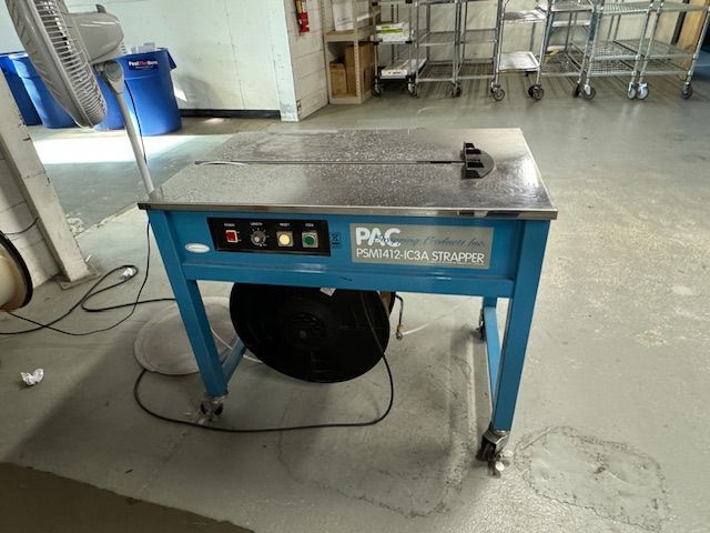 Blue PAC strapping machine with control panel, a roll of strapping,.