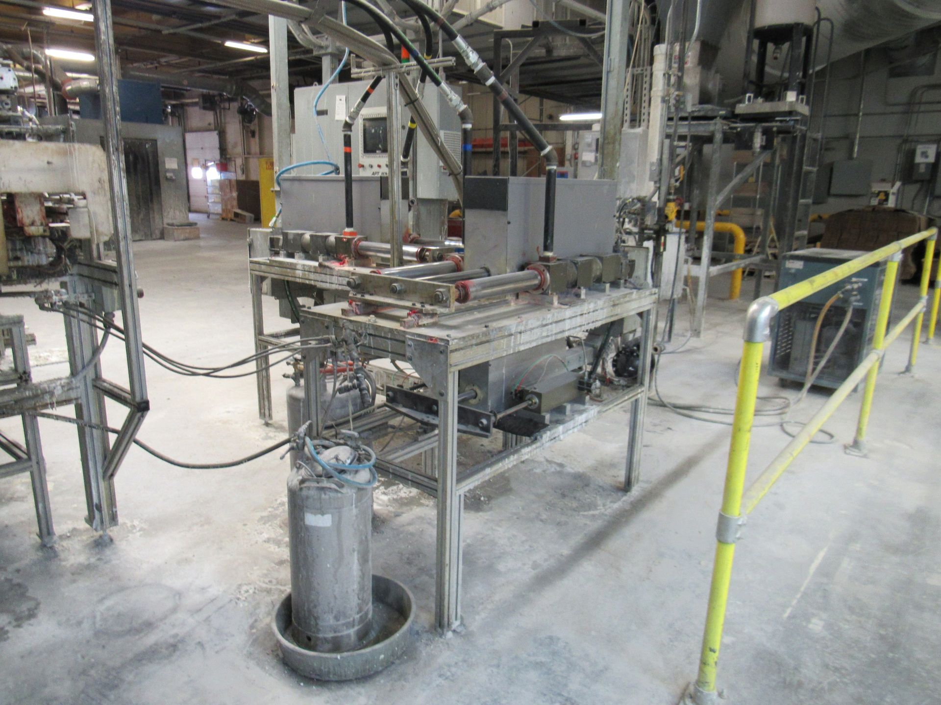 Machinery in an industrial setting; metal framework, various pipes, and controls.