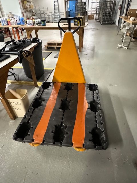 Orange and black pallet jack in a warehouse.