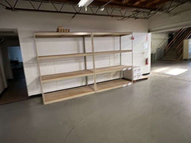Empty wooden shelves against a white wall in a warehouse.