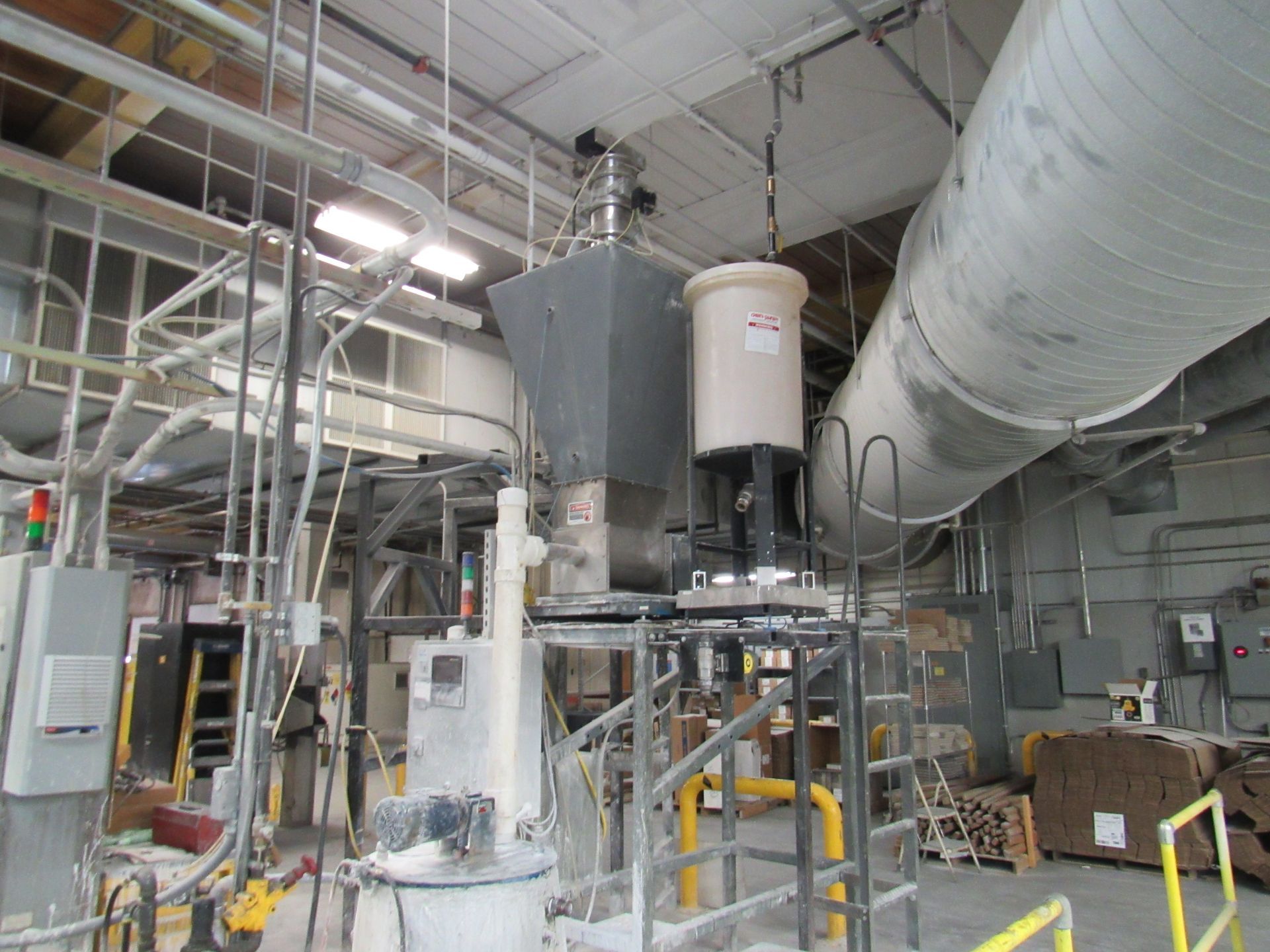 Industrial machinery with large gray and tan components in a factory setting.