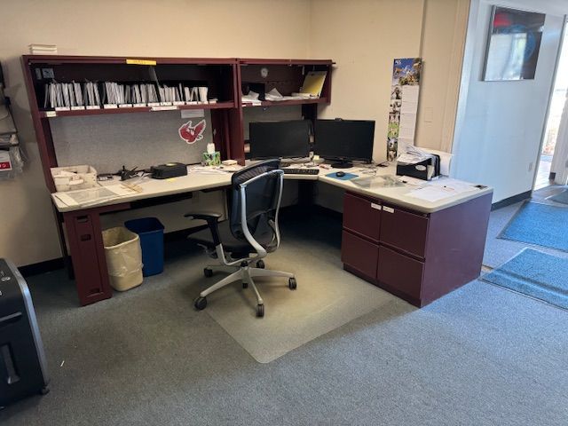 Office desk with dual monitors, file organizers, and a rolling chair.