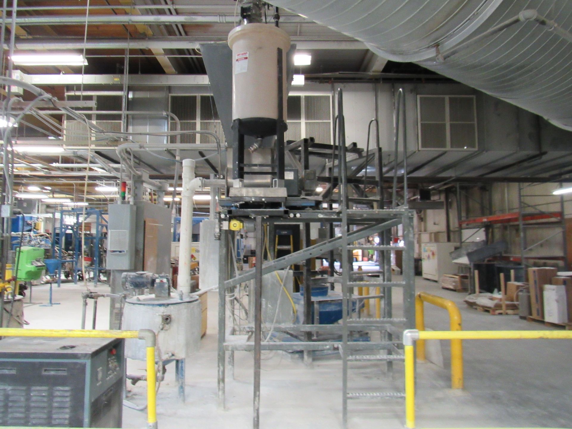 Industrial machinery in a warehouse setting, consisting of tanks, pipes, and metal scaffolding.