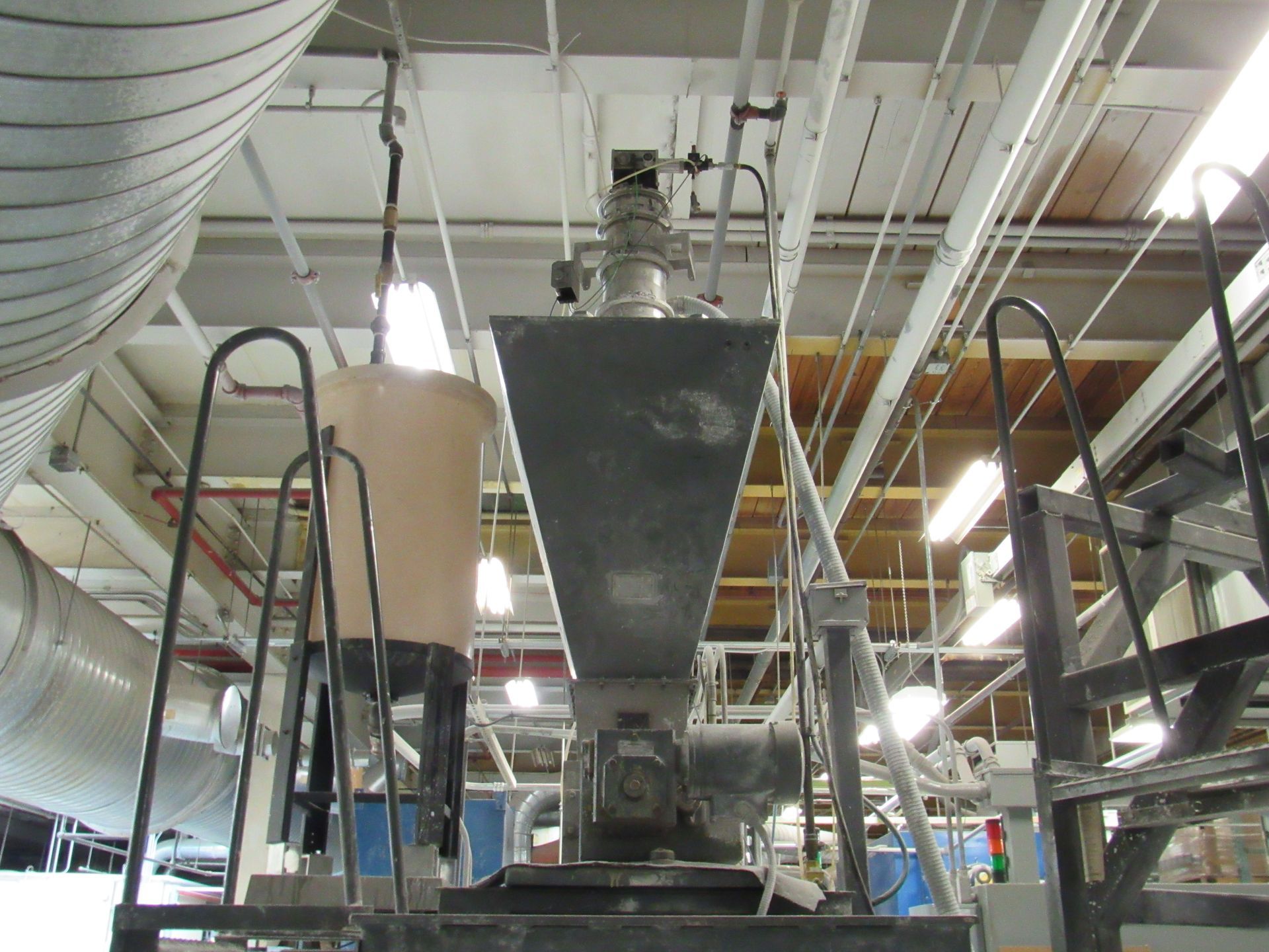 Industrial machinery with a hopper and conveyor system in a factory setting.