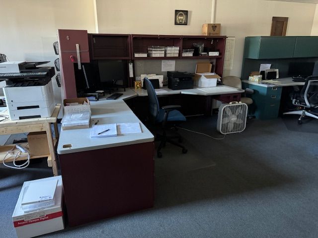 Office cubicles with desks, computers, and a fan.