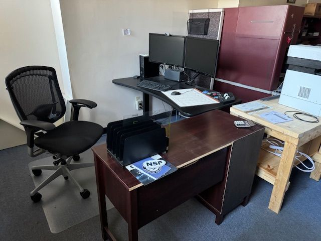 Office setup with desk, chair, dual monitors, computer, printer, and a maroon cabinet.