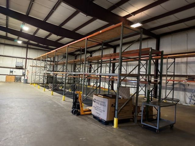 Warehouse interior with tall metal shelving and a hand pallet jack.