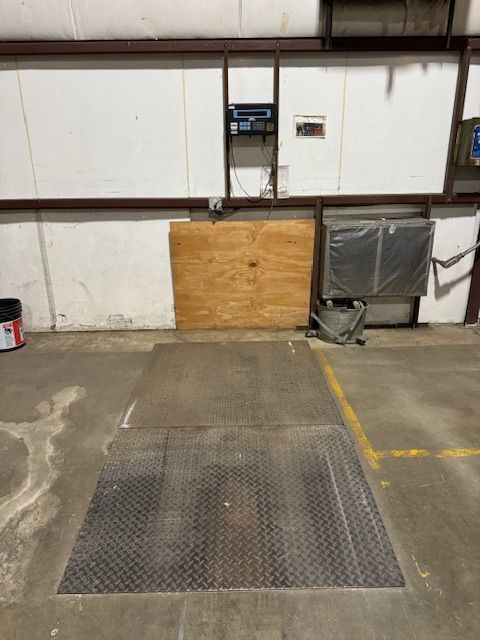 Loading dock with a metal platform and industrial equipment against a white wall.