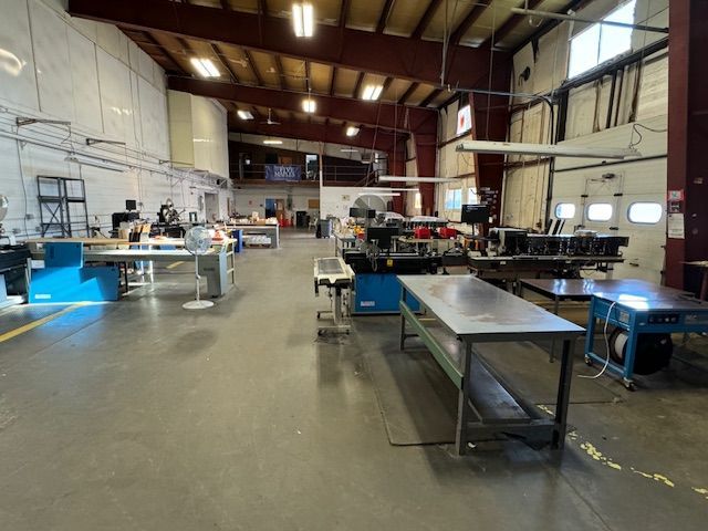 Workshop interior with machinery, workbenches, and overhead lighting.