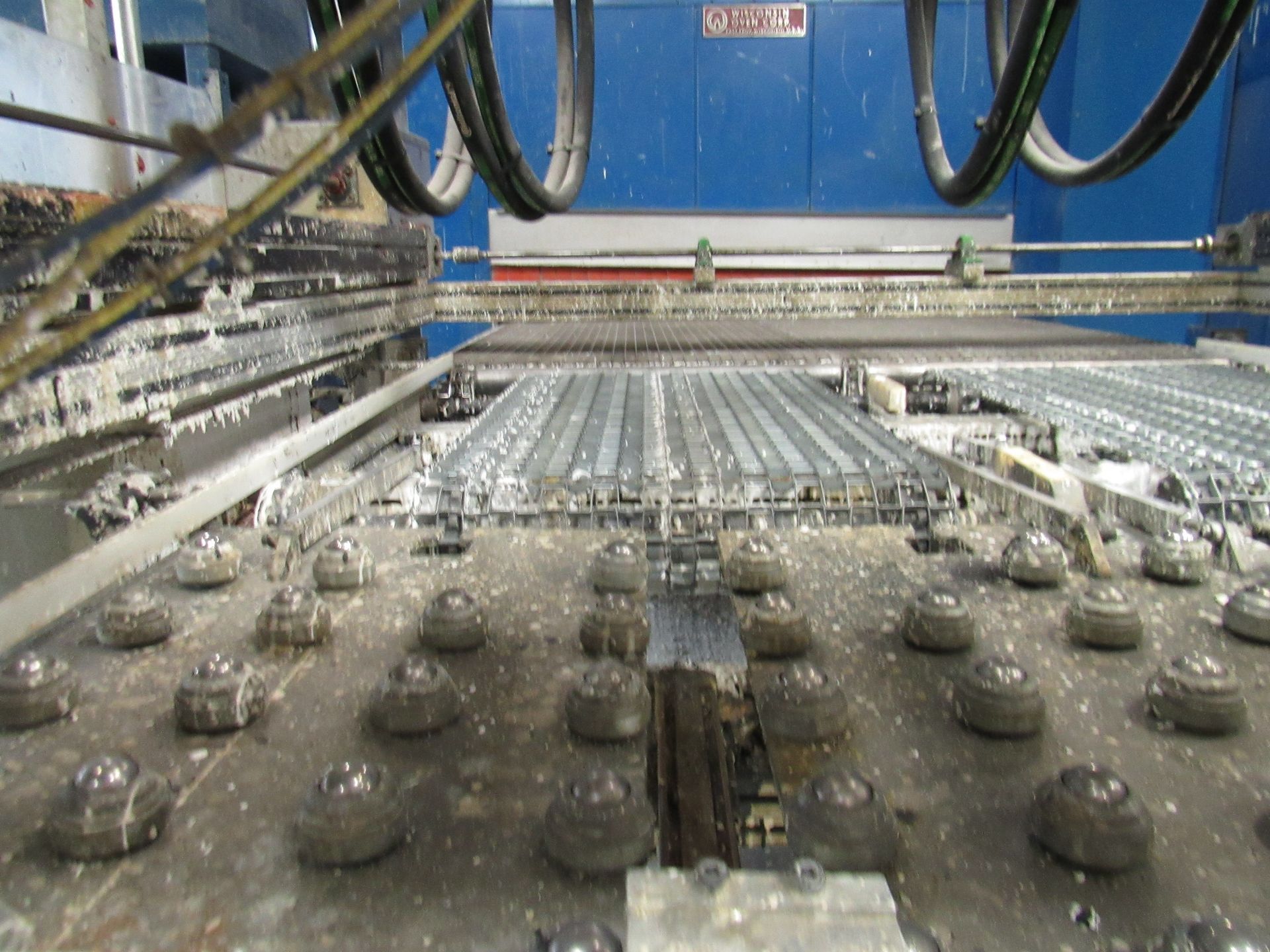 Industrial machinery spraying material onto metal forms in a factory setting.