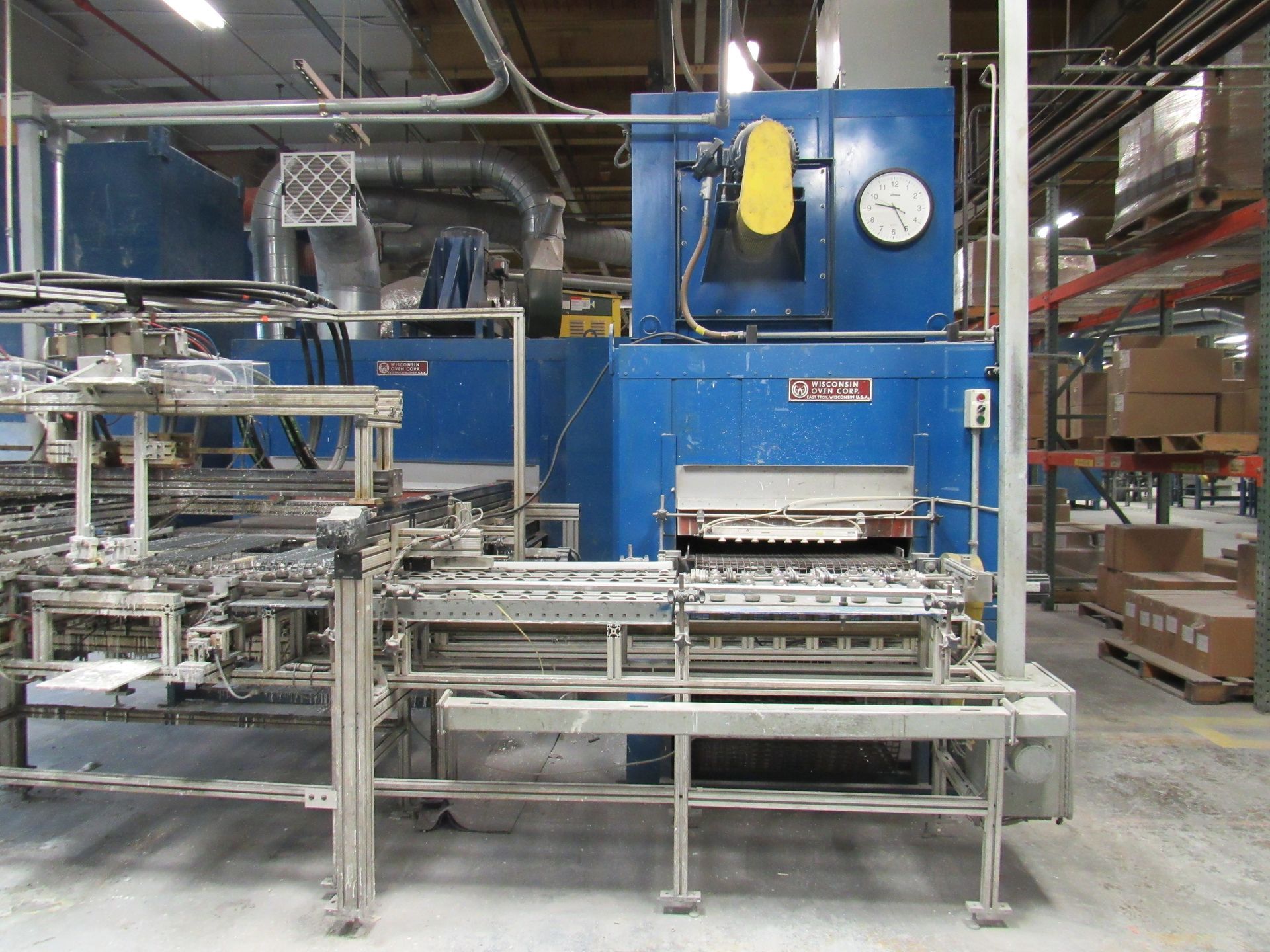 Blue industrial oven with automated conveyor system in a factory.