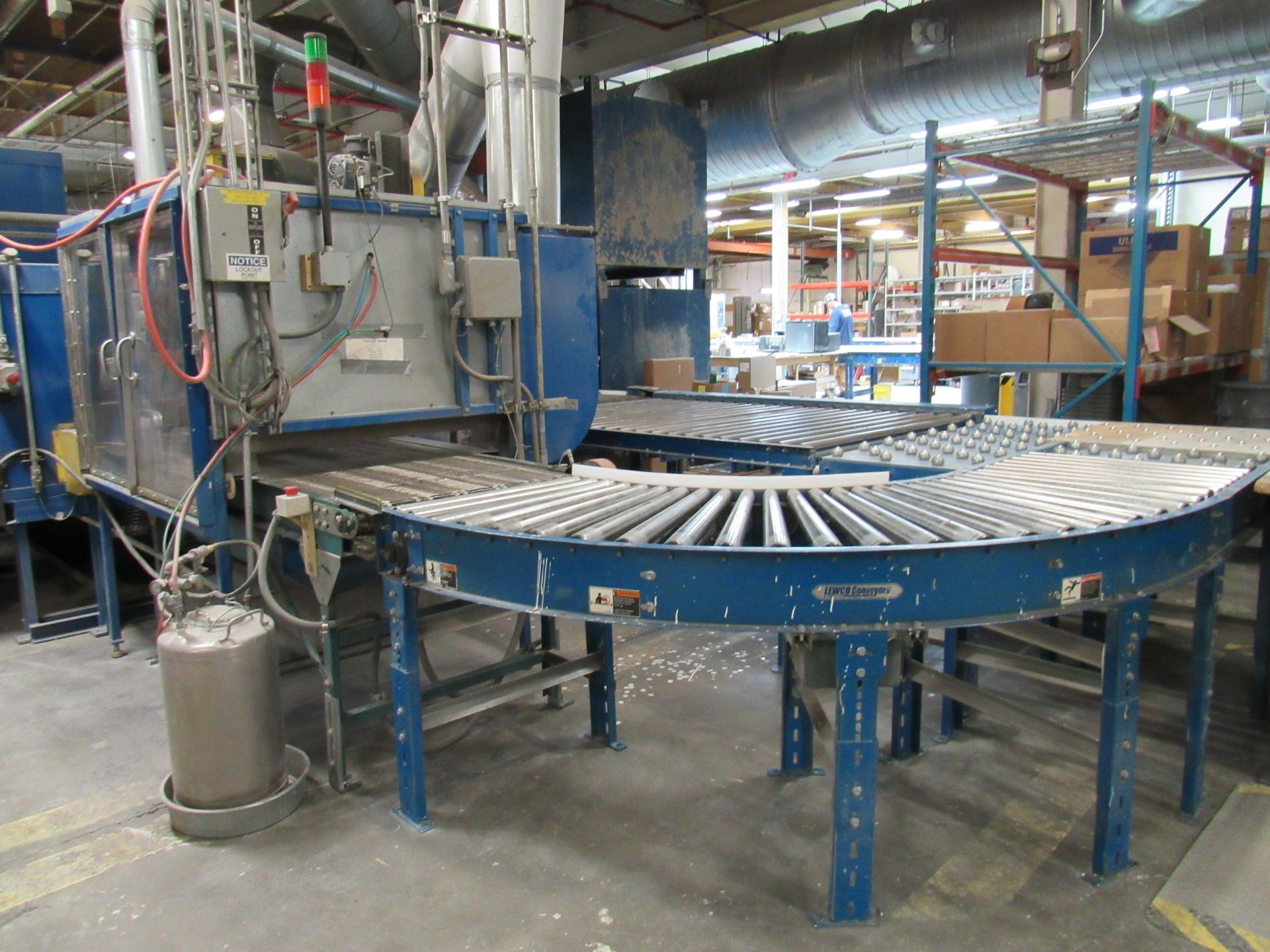 Industrial machinery with roller conveyor, blue and gray, in a warehouse setting.