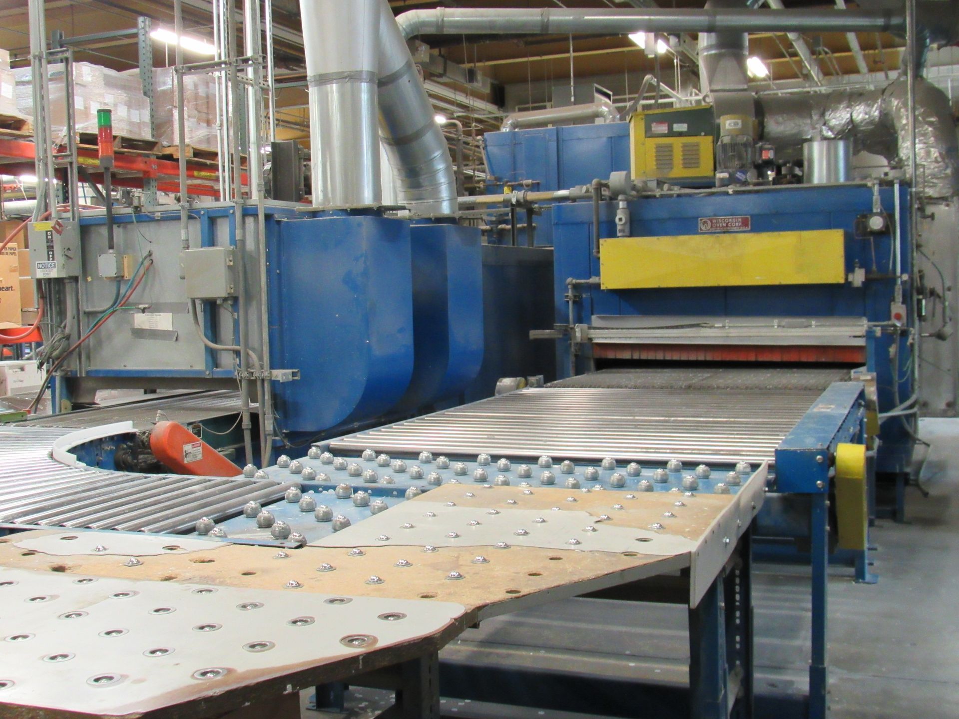 Blue industrial oven with a conveyor belt, used in a manufacturing setting.
